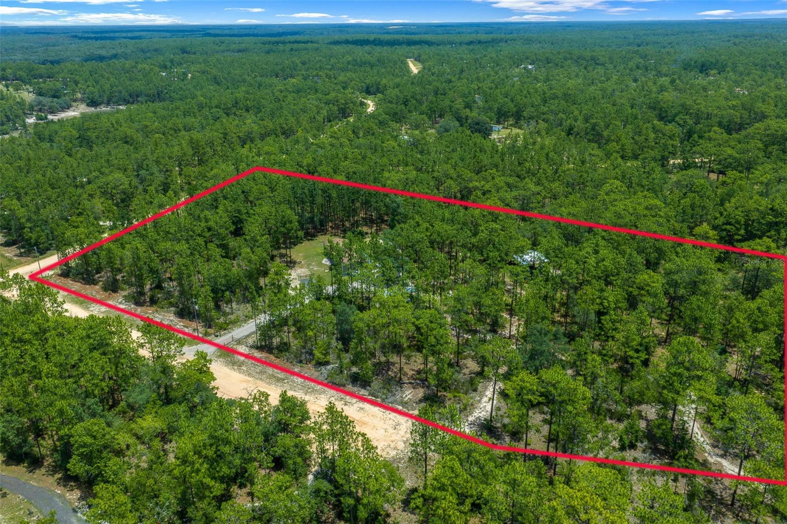 SPACE, PRIVACY, AND INFRASTRUCTURE—this 5+ ACRE AGRICULTURALLY ZONED property has ROOM FOR EVERYONE and everything. With 4 BEDROOMS, 3 BATHROOMS, a BONUS ROOM, and TWO LARGE COMMUNAL LIVING SPACES, the home offers a flexible layout designed for real life. The property infrastructure is already in place and thoughtfully planned. The partially cleared CORNER LOT backs up to conservation land with NO NEIGHBORS and offers access from both a dirt road, where it is the only house on the road, and a PAVED road. TWO GATED DRIVEWAYS with fresh stone lead to designated parking areas in both the front and back, with a mix of covered and open parking. The 30x30 POLE BARN includes a poured SLAB, electric, and water, while the 8x12 storage SHED with covered lean-tos and additional 5x8 SHED give you even more room for equipment, tools, and toys. You’ll also find two utility poles, a generator hook-up, a dedicated fire ring, and an expansive 46x12 COMPOSITE BACK DECK for outdoor living. Inside, the home has been thoughtfully updated with a NEW HVAC in 2022, NEW APPLIANCES in 2025, whole-home water softener, and high-speed fiber INTERNET. The Ring doorbell, washer, dryer, and stand-up freezer are included. Optional HOA is only $48/year and gives access to the lake for fishing, swimming, and kayaking. Private, practical, and well cared for—convenient to Starke, Keystone Heights, Palatka, Gainesville, and Ocala.