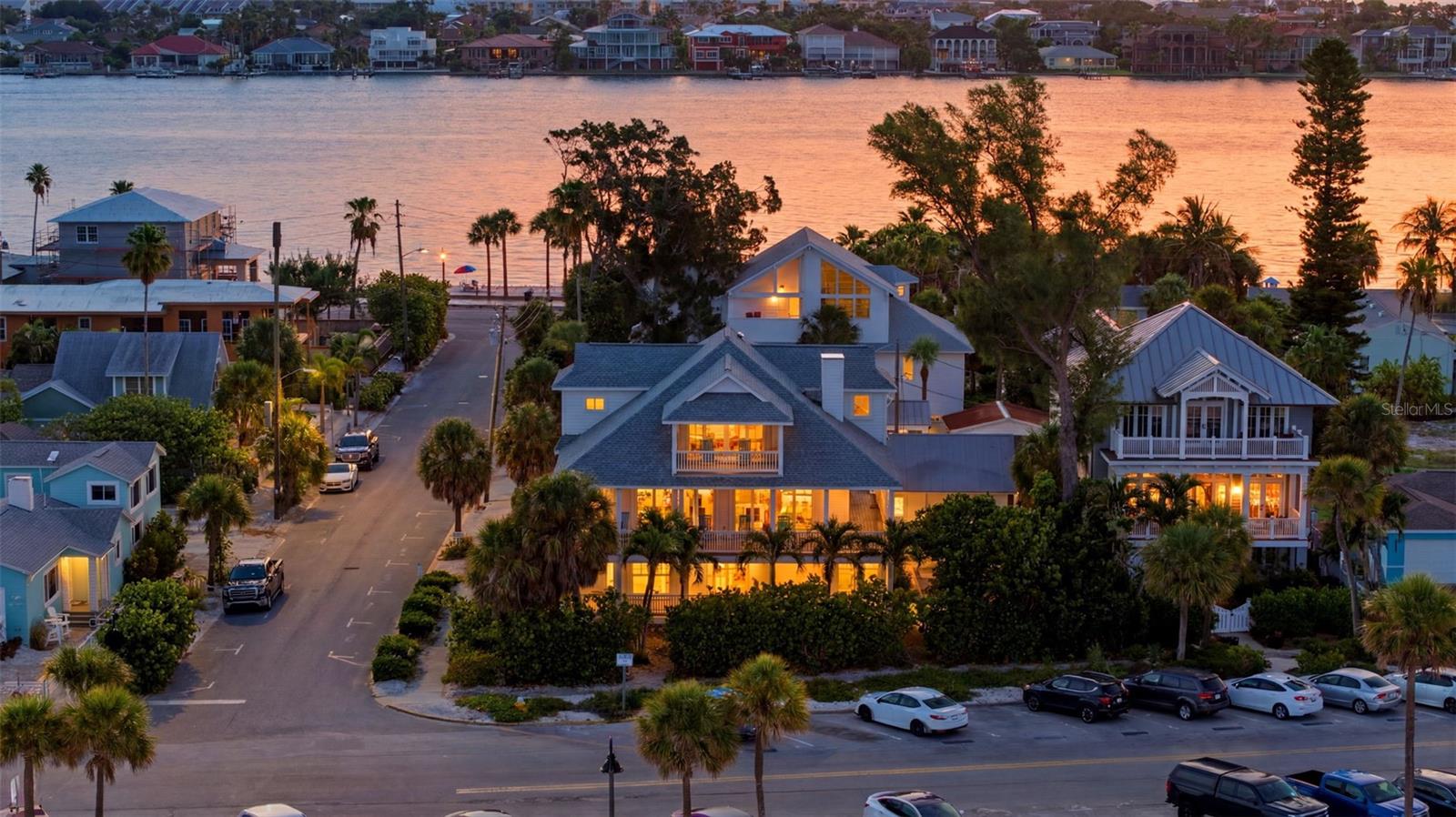 Nestled at the quiet southern tip of historic Pass-a-Grille Beach in St. Pete Beach, one of Florida's most treasured Gulf Coast communities, this magnificent Gulf-front estate offers the ultimate coastal lifestyle. Originally built during Florida's celebrated 1927 land boom and thoughtfully reimagined in 1999, this extraordinary residence blends historic character with modern luxury and includes an elevator serving all three levels. Positioned on a rare double corner Gulf-front lot (Lots 8 & 9) along iconic Gulf Way, the home captures breathtaking Gulf of America views from nearly every room. Three expansive covered decks provide the perfect setting for spectacular sunsets and refreshing sea breezes. Offering 4,724 heated square feet and nearly 7,800 square feet under roof, this five-bedroom, five-and-a-half-bath estate is designed for both grand entertaining and multigenerational living. The private ground level features its own entrance and can be locked off as a two-bedroom, two-bath guest suite complete with a full kitchen, spacious family room, and dedicated laundry, creating an ideal retreat for guests, extended family, or future rental opportunities. A transferable vacation rental/business license adds exceptional flexibility, although the current owners have enjoyed the property exclusively as a private family retreat. The main living level showcases a light-filled chef's kitchen appointed with two dishwashers, pot filler, built-in oven and microwave, ice maker, trash compactor, beverage refrigerator, walk-in pantry, and an adjoining butler's pantry with a second refrigerator, sink, washer and dryer, built-in desk, abundant cabinetry, and additional storage. Rich hardwood floors, volume ceilings, a fireplace, half bath, built-in flex space, and inviting gathering areas complete this level. The top floor is dedicated to a luxurious Gulf-front primary suite featuring two oversized walk-in closets, a private office, spa-inspired bath with separate water closets, and a large covered waterfront deck overlooking the Gulf. Outdoor amenities include a private shuffleboard court, outdoor shower, detached two-car garage, and an approximately 800-square-foot carport with ample space for vehicles, golf carts, beach equipment, and an RV hookup. Just moments from the boutiques, restaurants, and waterfront charm of historic 8th Avenue, this remarkable residence offers a rare opportunity to own an iconic Gulf-front estate in Pass-a-Grille. A timeless legacy property where history, luxury, and unforgettable beachfront living come together. Additional details include a new roof, new porcelain tile wood look flooring and remodeled baths and kitchen on the firs floor, new hurricane sliding doors on the first floor, new appliances in the guest suite and so much more!