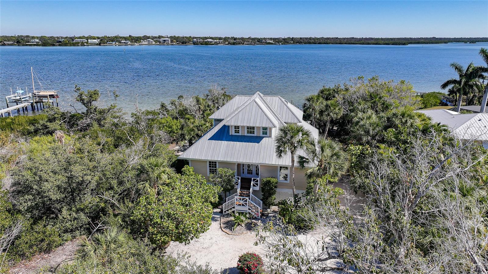 An exceptional offering on Manasota Key, this refined waterfront
residence delivers a lifestyle defined by privacy, elegance and a
setting that is “one with nature”.

Arriving via a 400 ft winding driveway through century oaks and
countless palm trees on Manasota Key is a private waterfront sanctuary.
The property captures the nature, beauty and serenity of old world
Florida. The home is set on nearly one acre and bordered by an
unbuildable neighboring parcel.

Situated on one of the widest points of Lemon Bay, the home enjoys
riparian rights extending over 1,200 feet into the bay that
forever protects your water view. There is a private L-shaped boat dock
- ideal for boating enthusiasts seeking bay and gulf access with no
fixed bridges.

Directly across the street is a 6ft deeded beach access easement. The
home is far from public access in both directions so your beach is about
as private as they come. 

The residence was renovated top to bottom in 2023-2024 and designed with
both elegance and high quality finishes in mind. The first living level
sits at 13.4 feet, with Miami-Dade IMPACT-rated low-E, argon filled
windows certified to 200+ mph and an all hip metal roof, providing
confidence, serenity and style.

Inside, soaring ceilings and abundant natural light create an immediate
sense of openness and sophistication. Coastal finishes, luxury vinyl
flooring, and a wood-burning fireplace lend warmth and character, while
the layout flows seamlessly for both relaxed living and elevated
entertaining.

The owner’s suite occupies all of the top floor and is a private retreat
unto itself, featuring dedicated office space, generous closets and a
private balcony that captures breathtaking views across Lemon
Bay—perfect for sunrise reflections, daytime sun bathing and evening
star gazing.

Additional amenities include: • Covered parking for 4 cars • Generous
under-home storage and workshop • Central vacuum system • Alarm and
exterior video security system.

This is a home that offers not just beauty, but balance—where quiet
mornings on the bay, afternoons on a private beach and evenings beneath
expansive skies become part of everyday life. Located close to Manasota
Key’s celebrated dining, boating, and natural beauty, yet worlds away
from the ordinary. A rare coastal sanctuary, this property combines
architectural presence and serene beach living—an opportunity that
stands apart on Manasota Key.
