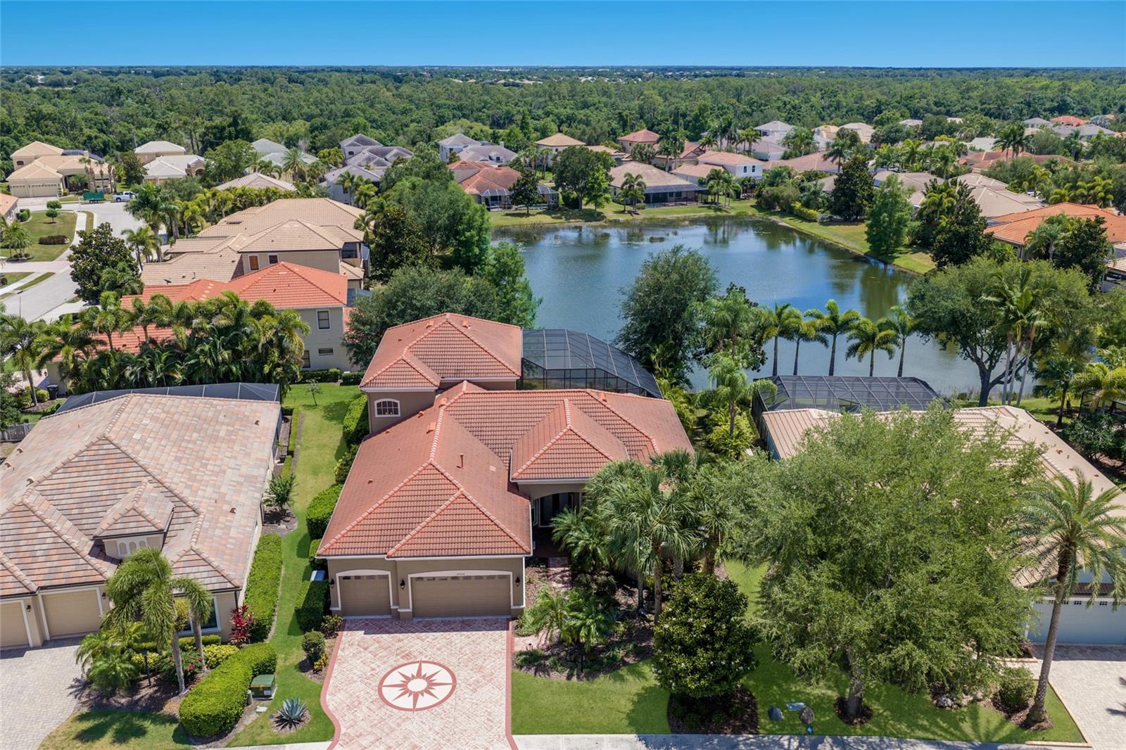 A home that lives like a private resort in the heart of Lakewood Ranch. Situated on a picturesque ¼ acre lakefront homesite in Greenbrook Village, this expansive 5-bedroom plus office and Media room, 4-bath luxury residence offers over 4,100 square feet of thoughtfully designed living space with exceptional indoor-outdoor flow and countless upgrades throughout. From the moment you arrive, the engraved driveway, mature landscaping, and dramatic evening landscape lighting create unforgettable curb appeal.
Inside, etched French doors open to soaring 12-foot ceilings, abundant natural light, tray ceiling details, and sweeping views of the pool and lake beyond. Designed for both entertaining and everyday comfort, the home features formal living and dining spaces, a spacious family room with disappearing sliders, and durable tile flooring throughout the main living areas.
The chef’s kitchen is beautifully appointed with quartz countertops, cherry wood cabinetry, newer appliances, a gas range, center island, and expansive breakfast bar ideal for gatherings large or small. The split-bedroom floor plan provides privacy for the luxurious primary suite, complete with direct lanai access, oversized walk-through closet, and a spa-inspired bath featuring dual vanities, garden tub, walk-in shower, and serene garden views from aquarium-style window. A private office or flex room, along with additional guest bedrooms and baths, complete the main level.
Upstairs, an oversized bonus room currently configured as a theater offers endless flexibility for a game room, lounge, or media retreat and is already plumbed for a future wet bar or kitchenette. Two additional bedrooms, a full bath, and a covered balcony overlook the sparkling pool and tranquil lake setting.
Outdoor living takes center stage with an impressive two-story screened lanai featuring programmable multi-color lighting, an infinity-edge pool with waterfalls and spa, shaded gathering areas, outdoor shower, and pre-plumbing for a future outdoor kitchen. The peaceful waterfront backdrop creates exceptional privacy and a true Florida lifestyle experience.
Additional upgrades include hurricane-rated windows and doors, a reinforced two-story pool cage, full-house generator, whole house water filter, tankless natural gas water heater, remote-controlled blinds, fresh exterior paint, and walkable attic storage with new 375-pound ladder access.
Perfectly positioned near Adventure Park, nature trails, playgrounds, dog parks, top-rated schools, Lakewood Ranch Main Street, UTC shopping and dining, Premier Sports Campus, golf, and the Gulf Coast’s renowned beaches, this home delivers space, luxury, and lifestyle in one remarkable offering.