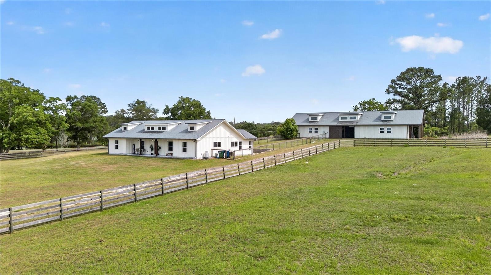 One or more photo(s) has been virtually staged. Some properties check a box or two. This one checks the whole list.
Tucked into Shaw Farms — one of Alachua County's most respected equestrian communities — this 6.28-acre hilltop property delivers the kind of setup that takes most horse owners years to piece together. The community sits along the edge of San Felasco Hammock Preserve State Park, putting miles of dedicated equestrian riding trails within reach without ever loading a trailer.
On the property itself, you have a jumping course, a dressage arena, paddocks, and a barn that means business. Six 12x12 stalls with automatic waterers and attached 12x12 individual turnouts. Two tack and storage rooms. Three separate entries. High ceilings. Already plumbed for a future bathroom and laundry. This barn was thought through — not thrown together.
The home sits at the top of the hill where the views do the talking. Both the front and back porch look directly out over the riding facilities and pasture. Inside, AquaGuard Performance Flooring covers every room — waterproof, pet-proof, and kid-proof, which is exactly what you want on a working horse property. Soaring ceilings with exposed hardwood beams anchor the great room. The dining room has a custom chandelier worth a second look. The kitchen is built around SMEG stainless steel appliances, generous counter space, and windows that pull the outside in from every angle.
There are 2 primary bathrooms each with an oversized walk-in closet have their own en-suite baths. The dual vanities have marble counters, and tile throughout with a separate tub and shower. The backyard is no-climb fenced, keeping dogs safe and well away from the paddocks.
When you are ready to leave the property, everything you need is close. Downtown Alachua and the Town of Tioga are minutes away for everyday shopping, dining, and errands. Gainesville is a short drive south, putting you near Fresh Market, Celebration Pointe, and Butler Plaza for retail and restaurants. Ichetucknee Springs State Park is roughly 30 miles northwest — one of Florida's most popular tubing and swimming springs. Ginnie Springs is about 25 miles away. For beach days, both the Gulf Coast and Atlantic Coast are within two hours.
For competition, the World Equestrian Center in Ocala is 52 miles south — close enough for regular show seasons without paying Ocala prices for the land. HITS Ocala is approximately 45 miles away, making this location practical for serious competitors on both circuits. UF Health Shands Hospital and North Florida Regional Medical Center are both a short drive from Shaw Farms.
This is the kind of property that does not need much of a sales pitch. The land, the infrastructure, and the location make the case on their own.