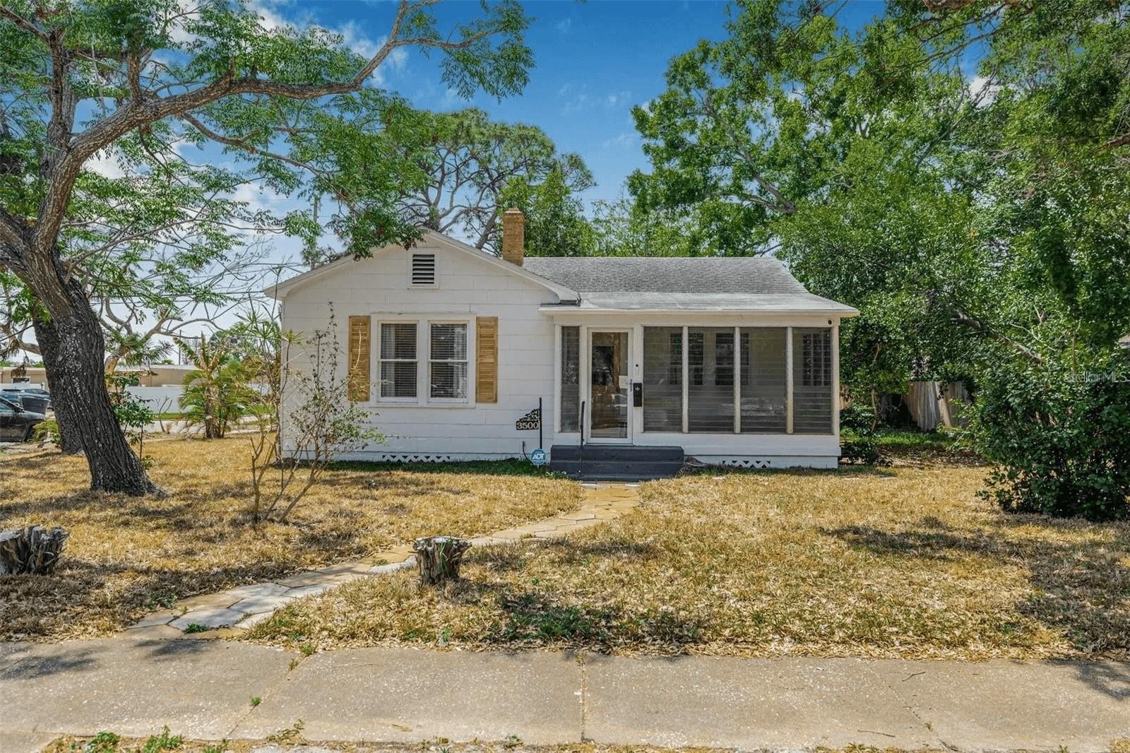 Welcome to this beautifully updated 1940s bungalow in the heart of North Kenwood — one of St. Petersburg's most sought-after, character-filled neighborhoods. Walkable, eclectic, and undeniably cool, North Kenwood sits right at the intersection of laid-back Florida living and everything that makes St. Pete one of the most exciting cities in the South. Three bedrooms, one bathroom, an attached garage, hardwood floors throughout, and a renovation that honors every bit of the home's vintage charm while bringing it firmly into the present.

Step through the front door and into the air-conditioned sunroom — the kind of space that immediately slows you down. Morning coffee, a good book, or just watching the neighborhood wake up. It sets the tone for everything that follows. With over 1,300 square feet of total living space including the gorgeous Florida room and garage, this home lives larger than you'd expect and uses every inch intentionally.

Inside, the living room is anchored by a classic brick fireplace surrounded by natural light and original hardwood floors that have been loved for decades. The layout flows effortlessly through arched entryways into a formal dining room that feels intimate and open at the same time — the kind of room that makes dinner parties feel easy.

Then there's the kitchen — and it is genuinely stunning. Sage green cabinetry with brushed gold hardware, quartz countertops, a double-basin farmhouse apron sink with a brass gooseneck faucet, open walnut floating shelves, and stainless steel appliances. It feels like it belongs in a design magazine. It's the heart of this home and it shows.

All three bedrooms carry the same warmth — hardwood floors, natural light, closet space, and a calm that makes each room feel like a retreat. The bathroom is crisp and thoughtfully updated with a vessel sink, matte black fixtures, and classic black and white tile that nods to the home's era without feeling dated.

A mudroom off the side entrance connects to the attached garage and in-unit laundry — practical, tucked away, and exactly where it should be.

Outside, the fully fenced 8,200 square foot corner lot gives you space that's genuinely rare at this price point in St. Pete. A private paver patio, room to entertain, room to garden, room to just exist — all tucked behind a fence in one of the city's most walkable and vibrant neighborhoods.

Steps from the Grand Central District, minutes from Downtown St. Pete, the waterfront, world-class dining, breweries, art galleries, and weekend farmers markets. This is the neighborhood people move to St. Pete *for*.

**Vintage charm. Modern soul. North Kenwood. Don't miss this one.**