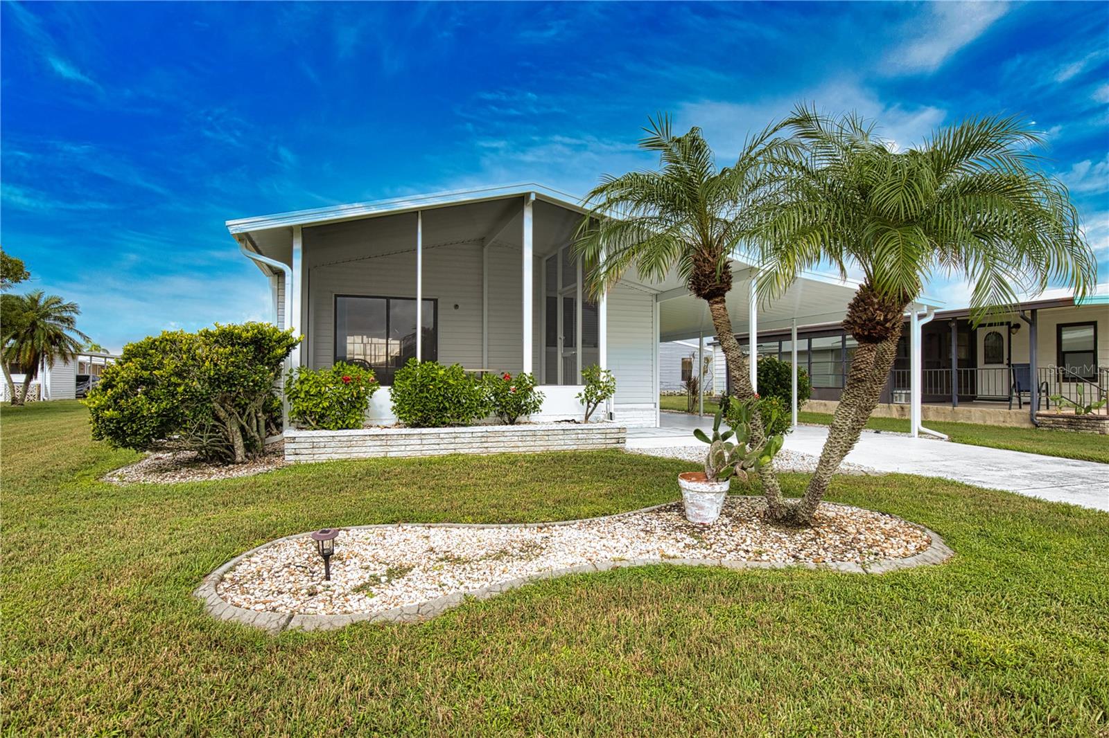 Enjoy the La Casa lifestyle in this charming, well-kept two-bedroom, two-bathroom home. A new carport and long driveway lead to an expanded utility room with a workbench, storage, washer, dryer, and a deep sink. The entryway includes a bench with storage underneath. The spacious kitchen offers a double pantry, breakfast bar, appliances, and a pass-through window to the Florida room. Next to the kitchen, the dining room has a built-in hutch for your special items. The bright living room features a sliding door to the glass-enclosed Florida room, which is cooled by a wall A/C unit and has doors to the front walkway and a patio area. The guest bedroom has a large wall-to-wall closet, and the guest bathroom includes an accent wall, vanity, tub/shower combo, and linen closet. The primary bedroom has a large walk-in double closet, and the ensuite bathroom features a garden tub, a double-sink vanity with a tiled countertop, wood accent walls, and a spacious walk-in shower. The roof was replaced in 2023, and the water heater is about four years old. This lovely home also includes A/C, a humidistat, ceiling fans, and vaulted ceilings throughout. Exclusions include Tiffany Lamps, collectibles, and wall decor. A beautifully maintained home.  The Community of La Casa, where 974 stunning homes are elegantly nestled among a tapestry of native trees, offers a serene escape surrounded by spacious common areas and eight picturesque lakes. La Casa is perfectly situated between Sarasota and Fort Myers, and embodies the ultimate lifestyle on Florida’s Gulf Coast—a true boaters paradise with access to the breathtaking Gulf of Mexico. Enjoy the convenience of nearby shopping, exciting sightseeing, world-class golfing, and abundant fishing and boating opportunities, all while indulging in the rich culture and refined elegance for which Southwest Florida is celebrated. As you immerse yourself in the warmth of Southwest Florida’s winters, you’ll find yourself in a relaxed and unhurried atmosphere, far removed from the hustle and bustle of the east coast. Our community is adorned with lush, mature landscaping that reflects the loving care both residents and management dedicate to preserving its beauty. Stay connected while basking in the sun with our complimentary wireless Internet (Wi-Fi), available at the Clubhouse, Activity Building, and Recreation Hall. Whether you’re catching some rays or catching up on emails, La Casa has it all. Does this sound appealing? La Casa is not just a community; it’s a welcoming family-friendly haven.