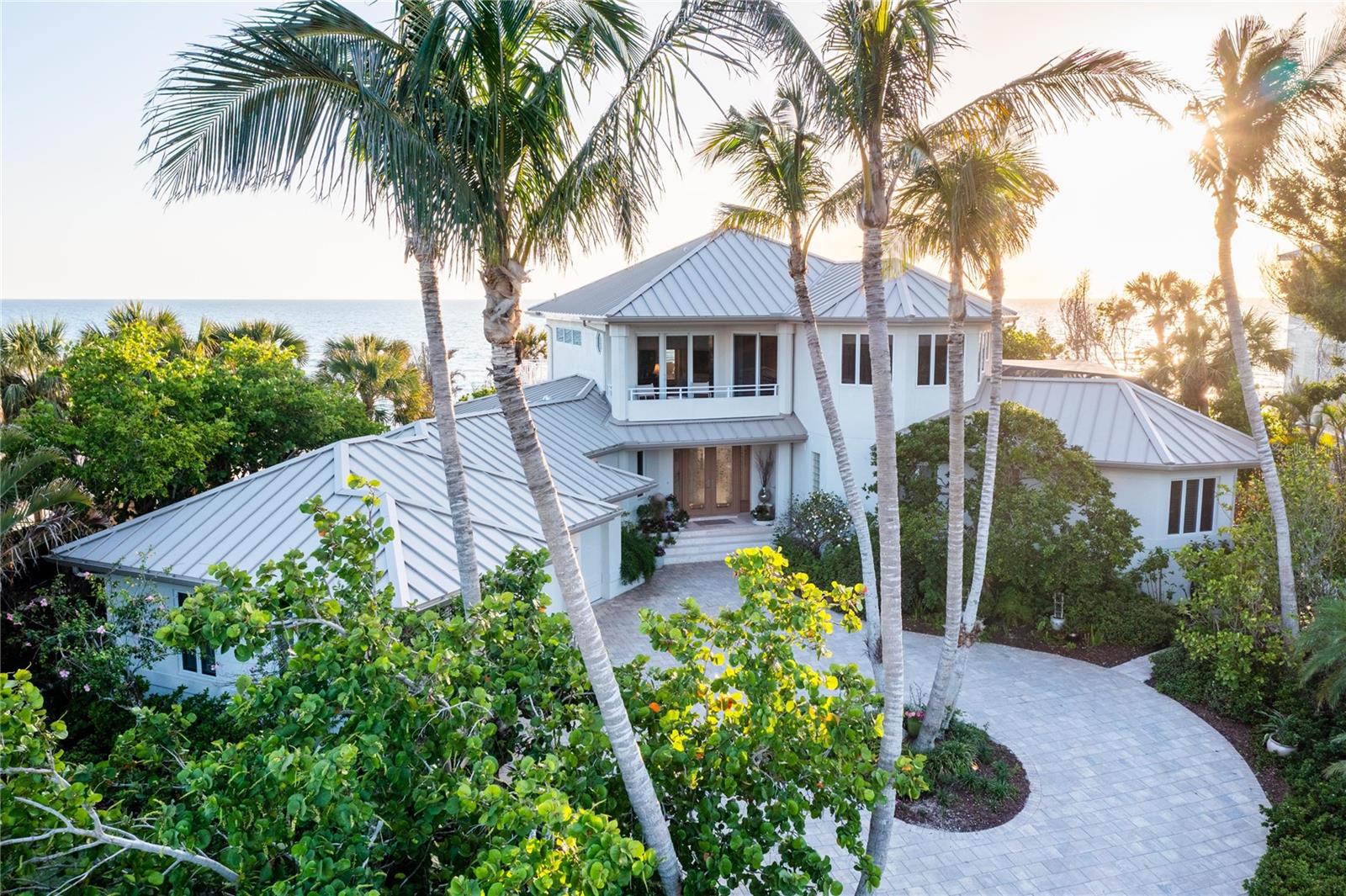 Welcome to your own private coastal retreat—where your backyard is the beach and every day feels like a getaway. This rare, direct beachfront estate on North Manasota Key delivers the ultimate in tranquility, seclusion, and barefoot luxury on one of Florida’s most coveted barrier islands.

Tucked within an exclusive, gated community of fewer than 80 homes along a serene two-mile private road, this property offers a lifestyle defined by natural beauty and relaxed elegance. With approximately 135 feet of pristine Gulf frontage and 147 feet on the Bay, all set on more than an acre of land, this elevated haven (rising 15 feet) captures the essence of true coastal living. NO DAMAGE OR WATER INTRUSION IN THE HOUSE FROM HURRICANE HELENE OR MILTON!

Step inside to 4,533 square feet of sun-drenched interiors where panoramic water views steal the show. An open-concept layout connects the main living spaces, perfectly designed for hosting and relaxing—whether you’re gathering around the dining table or savoring morning coffee with nothing but sea and sky in view.

The chef’s kitchen features generous cabinetry, new Dolomite countertops, ample storage, and windows that frame both the Gulf and the pool, blending indoor comfort with natural inspiration. Just outside, the shell-stone lanai is your private oasis: a heated pool and spa surrounded by lush native gardens, a built-in Wolf grill, skylights for natural light, and a pool bath for added convenience—all just steps from the sand.

The home’s thoughtful layout provides separation and privacy for family and guests. Two ensuite bedrooms on the ground floor are positioned in their own wings, while a flexible third ensuite—currently used as a den—can easily become a fourth bedroom, also having a large storage closet and beautiful Gulf views. Upstairs, the spacious master suite is a peaceful retreat with stunning beach and bay views, with a two-sided fireplace, sitting area, spa-like bath, and a private Brazilian walnut wood deck overlooking the Gulf. A second covered balcony on the bay side and a refined office with custom built-ins round out the upper level.

Meandering stone paths wind through lush, newly landscaped grounds adorned with vibrant orchids and native palms, guiding you to a brand new beach walk-out and your own secluded stretch of sand. A thoughtfully engineered sand berm provides vital protection against beach erosion, offering peace of mind and preserving your pristine shoreline for years to come. Along the way, discover multiple shaded and open-air sitting areas—perfect for morning coffee, sunset views, or simply soaking in the serenity of this coastal haven. Here, you can stroll the shoreline in search of seashells and shark’s teeth, watch dolphins play at sunset, or simply unwind with your toes in the sand. On the bay side, your recently resurfaced private dock (2024) and upgraded 10,000 lb boat lift (2023) offer endless opportunities for boating, fishing, or paddleboarding.

Though it feels a world away, you're just minutes from golf, tennis, dining, boutique shopping, and top-rated schools.

This is more than a home—it’s a beachfront sanctuary, where life slows down and every day feels like a vacation.