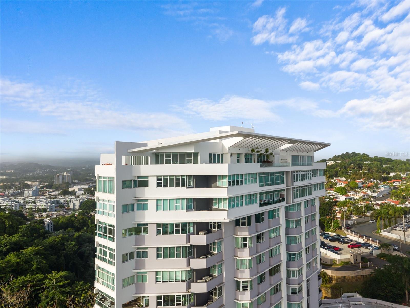 Crowning the skyline within the sough after La Cima de Torrimar, a landmark condominium designed by a renowned local architectural firm and recipient of the XV Cemex Building Award in 2006, this exceptional two-level penthouse offers an unparalleled blend of scale, elegance, and breathtaking panoramic views. Spanning 5,312 square feet, including an expansive 1,181-square-foot private terrace, the residence enjoys one of the building’s most desirable orientations, capturing abundant natural light and sweeping 180 degree north facing views.
Designed for both comfortable living and grand entertaining, the penthouse features four spacious bedrooms, a dedicated office, and four-and-a-half bathrooms. Marble floors run throughout the residence, while a dramatic double-height living room creates an immediate sense of grandeur, with soaring ceilings and an open architectural design that connects both levels and fills the home with natural light.
The main level offers elegant living and dining spaces, a well-appointed kitchen, and an oversized primary suite featuring separate his-and-hers walk-in closets. The residence also offers the rare convenience of direct access from both the 19th and 20th floors.
The upper level features a spacious family room, a secondary kitchen, dedicated office space, and direct access to the expansive terrace, an ideal setting for outdoor dining, entertaining, or simply enjoying the spectacular views and year-round Caribbean breezes.
La Cima de Torrimar is one of Guaynabo’s most established and sought-after condominium communities, offering 24/7 security, a swimming pool, fitness center, visitor parking, full power generator, and water cistern for complete peace of mind. The penthouse includes three deeded covered parking spaces and electric vehicle charging capability.
Ideally located in the heart of Guaynabo with immediate access to major highways, premier schools, restaurants, shopping, and San Juan, this residence offers the perfect balance of privacy, convenience, and sophistication. A rare opportunity to own one of the finest penthouse residences in Guaynabo.
