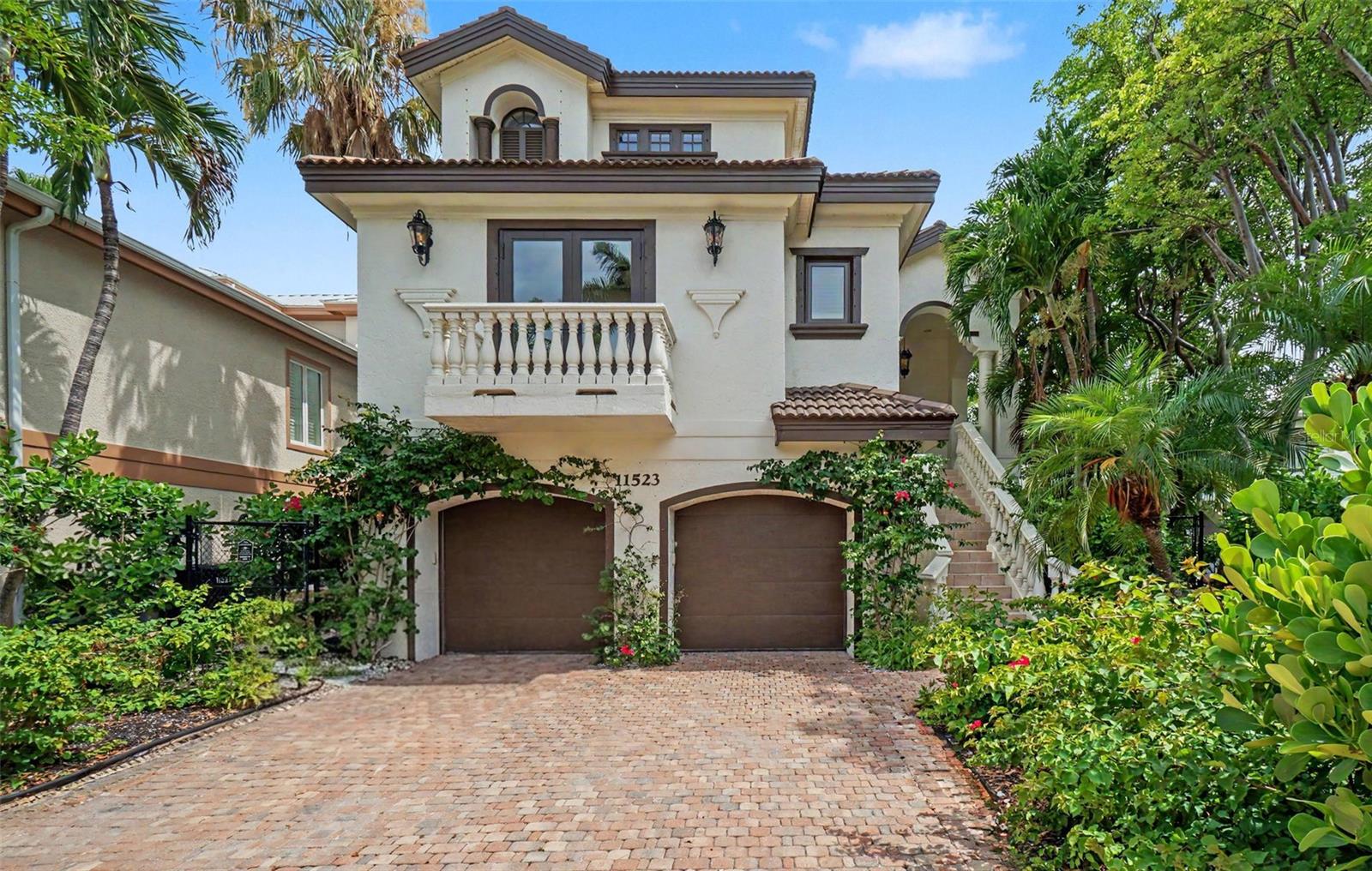 Virtually Staged. Welcome to one of Captiva Island's most remarkable residences: a stunning Mediterranean-inspired estate nestled on the legendary Andy Rosse Lane, just steps from the Gulf of Mexico. Move-in ready and finished with fine stylings throughout, this multi-level home delivers the perfect blend of luxury island living, flexible accommodations, and exceptional investment potential as a short-term rental.  Arrive via a classic paver brick driveway framed by lush tropical landscaping, climbing vines, and colorful blooms. The stucco façade, clay tile roofline, arched garage doors, and elegant balustrade balcony set a tone of timeless sophistication from the moment you pull in. A grand staircase sweeps up to the main entry, while a private elevator services every floor of the main house for effortless access. The ground level features a spacious two-car garage with ample storage, a large recreation room perfect for a game room, media lounge, or fitness space, and a full en suite bathroom, ideal for guests or extended stays without ever needing the upper floors. The heart of the home unfolds across a sweeping, light-filled main level featuring large-format travertine tile, soaring coffered ceilings, and graceful arched doorways. Dual chandeliers anchor a dramatic tray ceiling above the open-concept living and dining room, a space bathed in natural light through picture windows and French doors that open to the outdoors. The gourmet kitchen is a chef's dream, offering custom white cabinetry, a generous island with breakfast bar seating, a walk-in pantry, and a bold statement range hood that adds a touch of artful color. Two well-appointed guest bedrooms, each with a private en suite bathroom, provide comfort and privacy for family and visitors alike. The main level is rounded out by a convenient laundry room and a powder half bath for guests. The entire top floor exemplifies refined luxury. The primary suite is a true sanctuary, featuring two expansive walk-in closets and a spa-caliber bathroom that will take your breath away. A dramatic black clawfoot soaking tub with polished chrome fixtures rests beneath a crystal chandelier, flanked by a dual-sink vanity with backlit mirrors, a rich marble tile surround, and a separate oversized walk-in shower. Glimpses of the tropical landscape through the primary bath's windows complete this private retreat. A fourth bedroom with its own en suite bath completes the top floor, perfect for a home office, nursery, or additional guest quarters. A covered balcony walkway connects the main house to a fully independent in-law suite, a rare and coveted feature on Captiva Island. This self-contained retreat includes a private bedroom, full bathroom, and kitchenette, making it perfect for extended family, a live-in property manager, or a dedicated short-term rental unit. Directly below the in-law suite, a pool bath and bonus room offer additional flexibility for outdoor entertaining, equipment storage, or a cabana-style hangout. Situated on Andy Rosse Lane, Captiva's beloved main street,  this home places you at the center of island life. Stroll to the Gulf beach in seconds, or walk to iconic local favorites like the Mucky Duck and the Bubble Room. Whether you're seeking a full-time residence, a personal island getaway, or a high-performing vacation rental, 11523 Andy Rosse Lane checks every box. Properties of this caliber, in this location, rarely come to market. Schedule your private showing today.