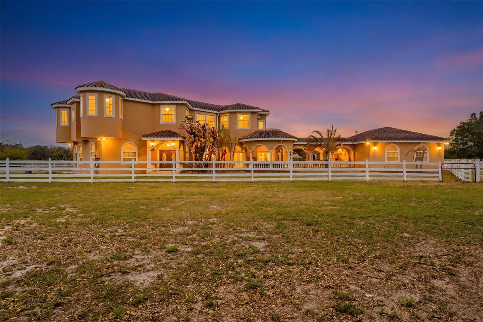 Set on five beautifully maintained acres in Groveland, this exceptional equestrian facility and private residence offers the perfect blend of luxury living and thoughtfully designed horse amenities. Ideally located just 45 minutes from Ocala and directly across from the private Grass Roots Airport, the property offers convenient access to hangars for rent or purchase and available runway usage.

The residence features four bedrooms and five full bathrooms, designed to capture sweeping views of the surrounding property. The expansive primary suite includes a wraparound balcony with incredible 180° views across the pastures and beyond, creating a peaceful private retreat. Each upstairs bedroom features its own en suite bathroom, while the downstairs suite offers a walk out covered balcony overlooking the pasture and pond, perfect for guests or multigenerational living.

The wide open kitchen serves as the heart of the home and is designed for both everyday living and entertaining, featuring granite countertops, a 36” Kenmore gas range with commercial grade hood, a professional size Kenmore refrigerator/freezer, and a large pantry. The residence also offers two laundry areas, including a full laundry room with built in shelving and hanging space, along with a separate laundry area ideal for handling horse related laundry. Modern comfort continues throughout the home with surround sound and recently updated HVAC systems.

Outdoor living is equally impressive. The backyard features a pebble tech pool with sun shelf, travertine decking, and a sunken spa beneath the covered lanai, complemented by a full summer kitchen with bar seating and a built in cocktail table gathering area. From the pool deck, enjoy tranquil views of the pastures, barn, and pond, creating the perfect setting for relaxing or entertaining.

The main barn and equestrian amenities are thoughtfully designed for both horse comfort and daily functionality. The barn includes automatic feeders, automatic waterers, and a fly spray system, along with five stalls equipped with air conditioning. Large ceiling fans in the center aisle and directional fans in the stall corners provide excellent airflow. The barn also features a climate controlled tack room, a dedicated grooming stall, and oversized 12 foot barn doors on both ends, allowing trucks and trailers to easily drive through.

In addition to the main barn, the property features three additional barns providing six more stalls, along with a large climate controlled storage room ideal for storing hay, grain, or equipment.

The property itself is fully fenced with no climb fencing and gated for security, with additional cross fenced four board fencing. Convenient walk through openings are placed at each gate so you can easily move throughout the property without needing to open horse gates. A comprehensive security camera system surrounds the property from the front entrance to the back pasture, allowing you to monitor the property remotely from anywhere.

This unique offering combines a luxury residence, a fully equipped equestrian facility, and exceptional privacy, all within convenient reach of Ocala’s world renowned horse venues, making it an outstanding opportunity for riders, trainers, and horse enthusiasts seeking both lifestyle and functionality.