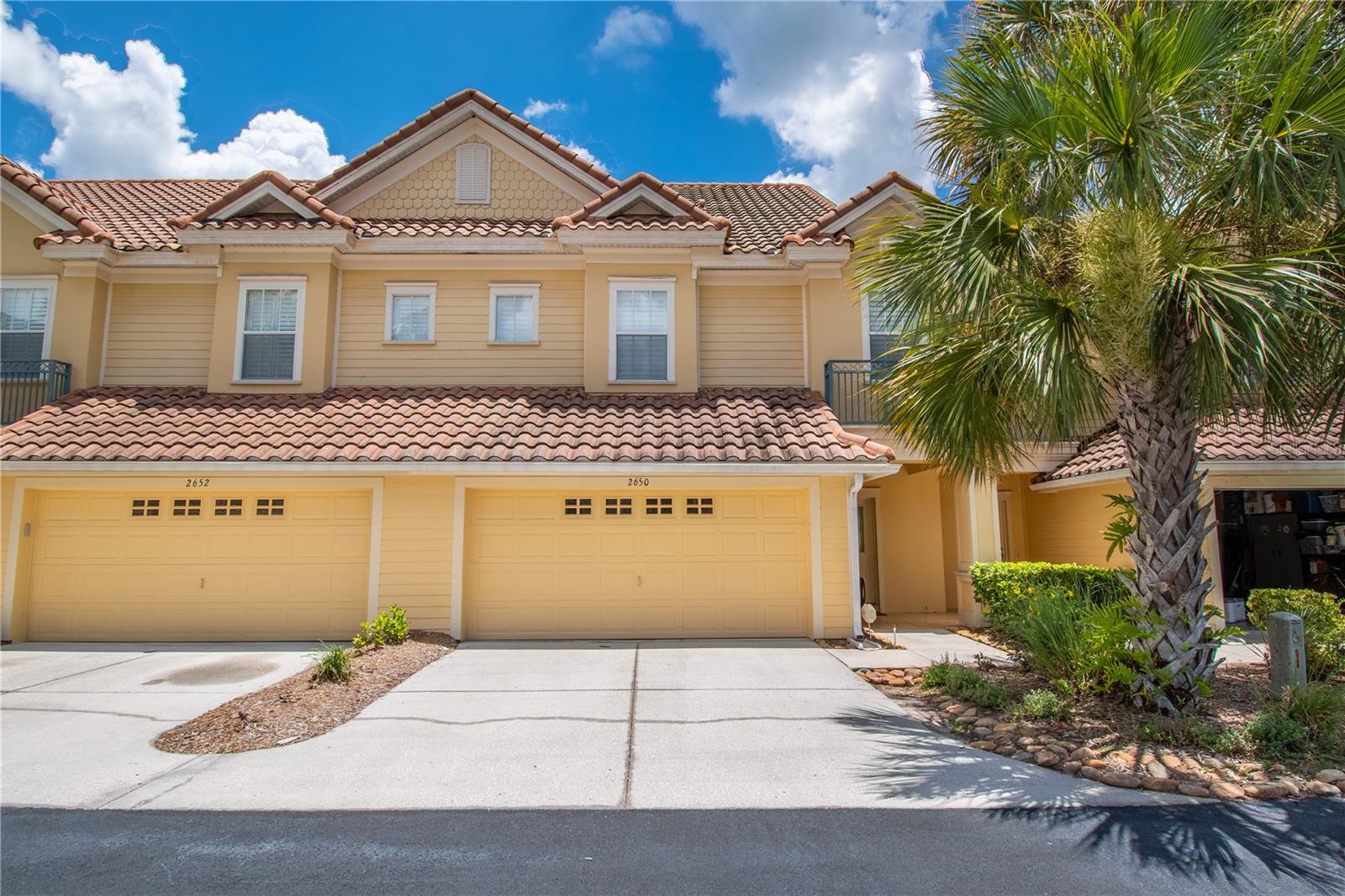 This Spectacular townhome nestled in a quaint 18-unit Mediterranean style, well maintained community. This must-see deal features: 3/2.5/2, with water and golf course views. The first floor has a well-designed open floor plan that boasts high ceilings, 1/2 bath, coat closet, oak wood flooring. The spacious Kitchen with garage access (with 2 oversize bays and epoxy flooring), solid oak cabinets and granite counter tops, the large dining area is separated by granite bar top that easily seats 6. The living room has a built in tv niche with ceiling surround sound speakers, a beautiful, paved courtyard with privacy wall. The second floor, also with high ceilings, features a large landing/loft tiled area with the laundry room and storage cabinets, two guest bedrooms and a full bath, with granite counter tops. The primary bedroom features water and golf course views, a gas fireplace and access to a relaxing, paved veranda with water/golf views, the tiled ensuite bathroom with a large shower and bench and has a garden tub. The double sink, solid wood vanity, has granite countertops, large walk-in closet, and a water closet.