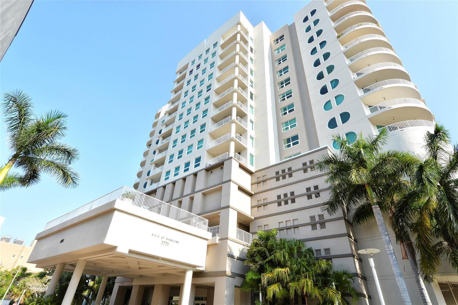 Perched on the 12th floor of the iconic Rivo at Ringling, this beautifully remodeled 2-bedroom, 2-bathroom plus den residence offers the ultimate downtown Sarasota lifestyle. Designed by the Rivoltas and executed by The ADP Group alongside architect Robert Towne, the building’s signature curvilinear shape and breathtaking 15-story indoor atrium flood the interior hallways with natural light through a massive center skylight. Step inside this high-floor urban sanctuary to experience an incredible sense of space, courtesy of rare 10-foot ceilings, which are a full foot higher than lower-level units. Elegant crown molding guides you into a fully remodeled gourmet kitchen featuring designer cabinetry, premium granite countertops, a seamless single-level dining bar, and an upgraded GE slide-in stove with a matching granite backsplash and designer vent hood. High-end culinary additions include an easy-access drawer microwave, a super-quiet dishwasher, a French-door refrigerator, and extensive lighting. Both bedrooms have walk in closets and there are plantations shutters throughout.  Both bathrooms have been completely transformed into spa-like retreats boasting beautiful custom tile work, massive walk-in showers, designer cabinetry, and high-end Toto toilets. The versatile den features classic French doors and its own closet, making it an ideal home office or a welcoming third sleeping space for overnight guests, while an oversized laundry and utility room provides extra space for a hobby area or secondary desk. Relax on your oversized tiled balcony facing east, allowing you to enjoy shaded outdoor dining without the intense afternoon sun baking your space. This unit includes premium conveniences like two deeded garage spaces, a large assigned storage unit, and access to dedicated indoor bicycle and kayak storage rooms, with stylish furniture available as an optional inclusion. Built on a robust pier-and-pillar foundation, the building ensures peace of mind with floor-to-ceiling, certified hurricane-proof sliding glass doors engineered for severe wind pressures. This premium impact glass also blocks UV heat transmission for low energy bills and provides total sound insulation from the city below. The third floor acts as your private oasis, housing top-tier amenities including a resort-style outdoor pool and spa, an outdoor grilling area, a fully equipped modern fitness center, and an elegant community club room. Enjoy absolute privacy with layered property security, including an automated garage gate, electronic key fob access, continuous digital surveillance, and a 24-hour concierge service with an on-site management team staffing the secure main lobby to provide concierge-style oversight for arrivals and package deliveries. Located just one block off Main Street, Rivo places the best of the city at your doorstep. You can easily walk to two premium supermarkets, over a fifty top-tier restaurants, five performance theaters, and a multi-screen movie house. The location is an outdoor lover's paradise, situated moments from the vibrant paths of Payne Park, the stunning waterfront promenade of Bayfront Park, and the premier recreation at Centennial Park, giving you immediate access to the 10th Street boat launch for quick days out on the water. This is a rare opportunity to secure a highly upgraded, walkable luxury lifestyle in the heart of downtown.