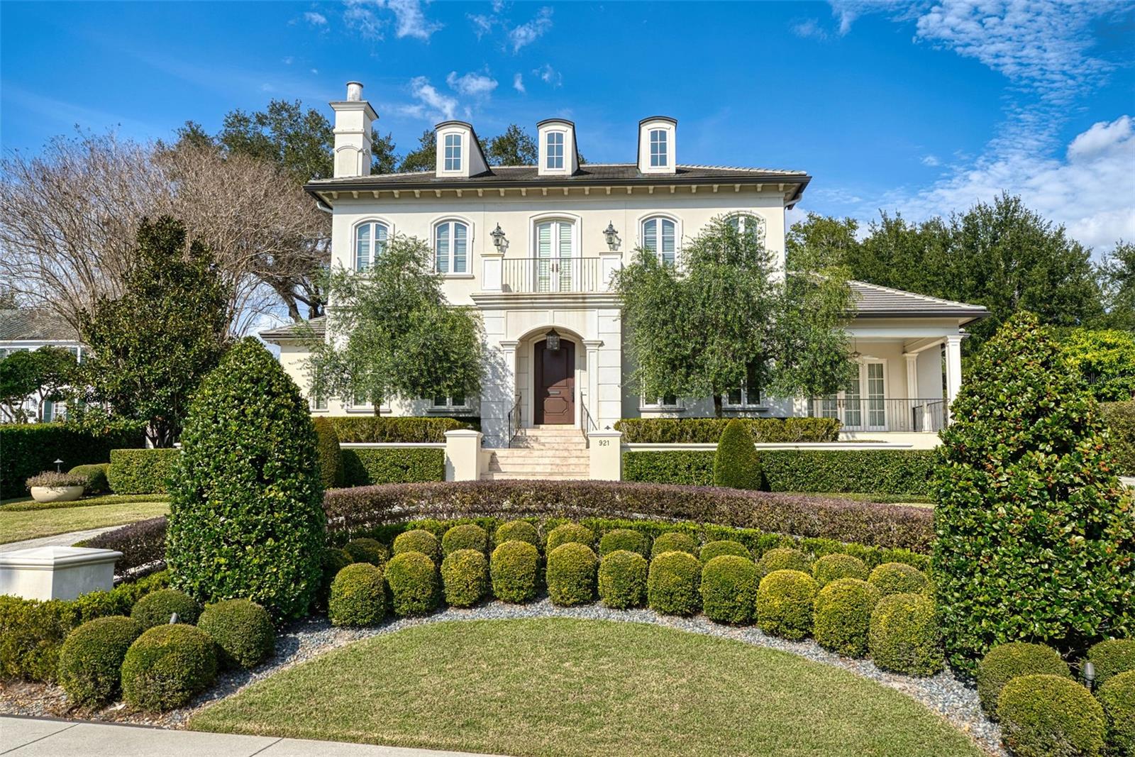 Distinguished estate residence overlooking Lake Adair in the heart of College Park. Built in 2015 by award-winning custom builder Goehring & Morgan, the home spans approximately .7 acres from N Lake Adair Boulevard to Oak Street and includes a private rear entrance. The thoughtfully designed floor plan features a main-level primary wing with two full bathrooms, two walk-in closets, and a study. Formal living and dining rooms are complemented by a large, well-appointed kitchen open to the family room, with French doors leading to a covered porch and private backyard. Upstairs includes three ensuite bedrooms, a sitting room with wet bar, and a bonus room above the garage. Architectural details include multiple fireplaces, hardwood floors, crown moulding, and custom built-ins throughout.