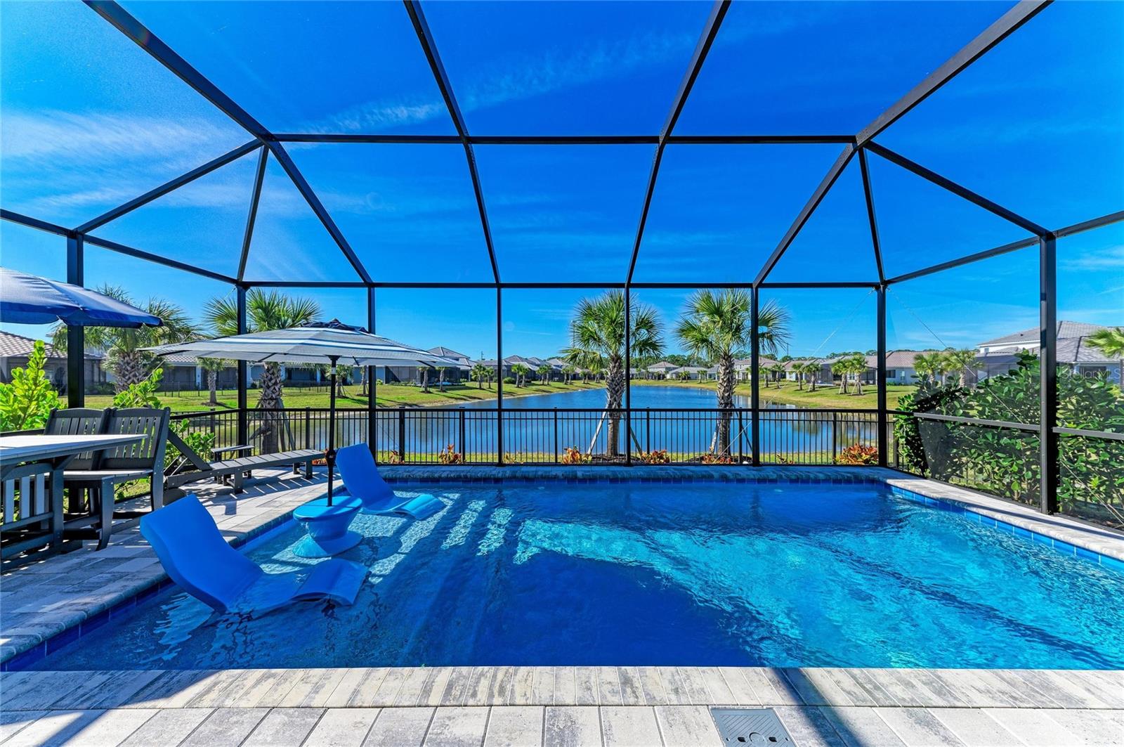 Embrace the incredible opportunity to own a nearly new 3 bedroom plus den home, complete with a delightful heated saltwater pool, all beautifully situated on a spacious lakefront lot. Imagine yourself taking in the stunning Florida sunsets from the comfort of your own backyard, what a perfect way to unwind after a long day! The generous wide homesite ensures privacy from neighboring properties and even features a fenced side-yard dog run, perfect for your furry friends to enjoy. Step inside this extraordinary residence, where you’ll be greeted by elegant luxury vinyl plank flooring in a rich honey hue that adds warmth and sophistication while requiring minimal upkeep, say goodbye to carpets! Marvel at the soaring ceilings, large baseboards, and intricate crown molding, all enhanced by plantation shutters on the windows, creating a bright and inviting atmosphere that feels just like home. At the heart of this home lies a beautiful kitchen that flows effortlessly into a spacious dining area. It boasts upgraded wood cabinetry with soft-close and pull-out features, stunning quartz countertops, a chic designer backsplash, and top-of-the-line stainless steel appliances, including a reverse osmosis system for your convenience, what more could a chef want? The expansive primary suite, conveniently located at the back of the house, offers serene views of the pool and tranquil lake, creating a perfect retreat. With a custom walk-in closet and a luxurious en-suite bathroom designed for relaxation, complete with a walk-in shower, dual sinks, and stylish mirrors and lighting, you'll feel pampered every day. The secondary bedrooms are equally impressive, featuring spacious walk-in closets and a shared bathroom that is perfect for family or guests. Efficiency meets practicality in the thoughtfully designed laundry room, equipped with built-in cabinets and a sink, convenience at its finest, strategically placed near the front of the home. The garage is an added bonus, designed with a 2-foot extension to comfortably fit larger vehicles or provide additional storage, and it includes a dedicated generator connection on the electrical panel for peace of mind. Nestled in the picturesque Grand Park neighborhood of Sarasota, Florida, developed by Neal Communities, this home beautifully celebrates the natural surroundings with lush, mature landscaping and ample outdoor spaces. Enjoy a wealth of resort-style amenities, including pools, a clubhouse, a fitness center, pickleball and tennis courts, dog parks, walking trails, and parks, everything you need to enrich your lifestyle! Plus, you’ll be just a stone's throw away from the gorgeous Suncoast beaches, shopping, dining, and the vibrant culture of downtown Sarasota. Don't forget that the recently opened Skye Ranch School, which offers a STEM curriculum, is nearby, making this an ideal location. This is more than just a house; it’s a dream lifestyle waiting for you! Call today to schedule your private showing and take the exciting first step toward making this amazing home yours!