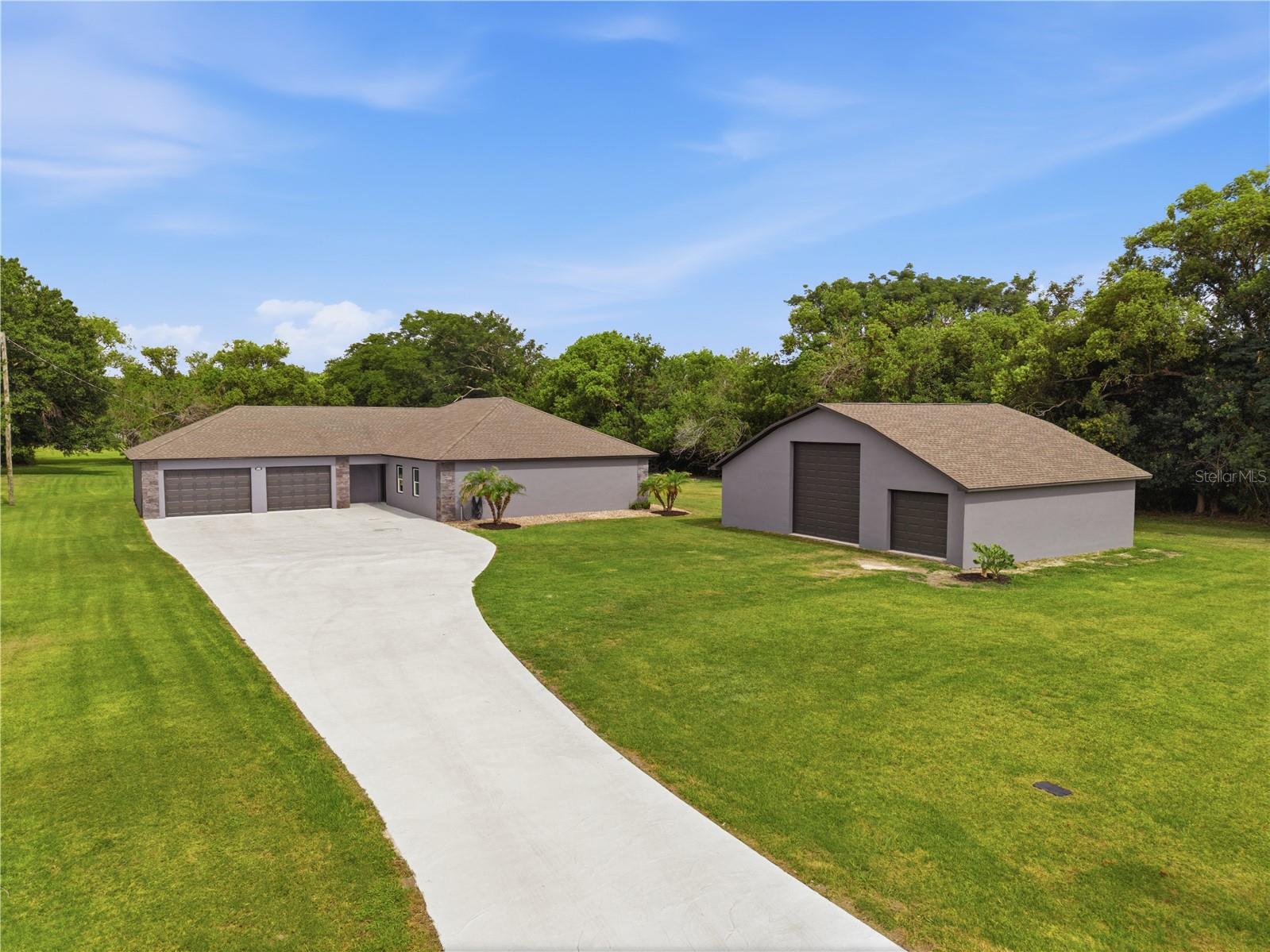 Exceptional custom-built home offering the perfect combination of quality construction, functional design, and impressive garage space, all situated on a full acre just minutes from town. This three-bedroom, two-bath residence features more than 1,800 square feet of living area and over 2,000 square feet of garage space. Upon entering, you'll appreciate the open-concept floor plan filled with abundant light. The custom kitchen is equipped with stainless steel appliances, granite countertops, a dedicated dining area, and a bar-top seating area overlooking the living room, creating an ideal space for both everyday living and entertaining. The spacious primary suite provides a comfortable retreat and includes a walk-in closet with custom shelving and an en-suite bath featuring a large walk-in shower. A split-bedroom layout offers privacy, with two additional generously-sized bedrooms and a full bath located on the opposite side of the home. Outdoor living is enhanced by a covered rear porch spanning 40 feet across the back of the home, providing ample space for relaxation and gatherings. The garage accommodations are truly remarkable. The attached oversized two-car garage offers 841 square feet and features custom flooring and recessed lighting. The detached 40' x 32' garage includes a center bay measuring 16' x 32' with 14-foot ceilings and a 12-foot overhead door, ideal for larger vehicles, boats, equipment, or recreational storage. The right bay measures 12' x 32', while the enclosed left bay provides an excellent workshop or hobby space. Additional quality features include spray foam insulation and exterior block walls reinforced with solid poured concrete, contributing to the home's durability and energy efficiency. Properties with this level of construction, garage capacity, and acreage are rarely available. Schedule your private showing today.