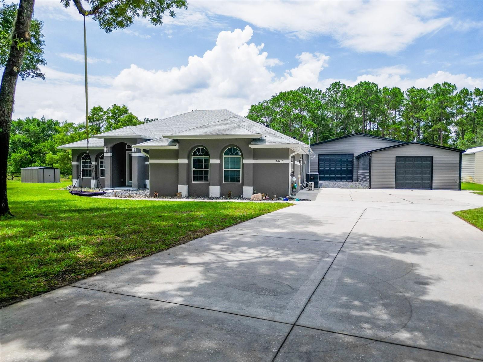 Virtually Staged. 3,100 SF Climate-Controlled Garage Complex + Pool Home on 1.04 Acres with Private Lake Access!

Welcome to your own private retreat beneath the oaks. Situated on a beautifully maintained 1.04-acre homesite with no rear neighbors, this exceptional property combines approximately 2,635 square feet of living space with an incredible 3,100-square-foot climate-controlled garage complex designed for collectors, hobbyists, entrepreneurs, and anyone needing serious room to live, work, and play.

Inside, you'll find soaring 12-foot ceilings, a split-bedroom floor plan, dedicated office space, and a spacious primary suite with private access to the lanai. The kitchen offers abundant cabinetry, breakfast bar seating, and a breakfast nook overlooking the pool. A private in-law suite with its own full bath provides flexible space for guests, multigenerational living, a home office, gym, or bonus room, creating a functional 4-bedroom, 3-bath layout.

Step outside to your own backyard oasis featuring a screened saltwater pool with custom shade sails, mature oak trees, and plenty of room for entertaining.

The true centerpiece of the property is the impressive 3,100-square-foot climate-controlled garage complex with a 5 ton HVAC in 2024. The main 40x60 building is insulated with 3" open-cell spray foam and features 12-foot walls, multiple overhead doors, compressed air lines, a floor drain, LiftMaster openers, a separate electric meter with 100-amp service, and an epoxy-finished workspace. The additional 20x20 garage and 20x15 connecting section provide even more flexibility for vehicle storage, projects, equipment, or a home-based business.

Recent improvements include luxury vinyl plank flooring installed in 2022, a resort-style saltwater pool added in 2022, a 2020 HVAC system,  well pump 2024 and water heater 2019. Additional features include Spectrum fiber internet, a six-zone irrigation system, horse zoning, and private access to Lake Norris for boating and fishing.

Whether you're a car enthusiast, RV owner, contractor, small business owner, or simply someone looking for space and privacy, this one-of-a-kind property delivers a lifestyle that is becoming increasingly difficult to find.