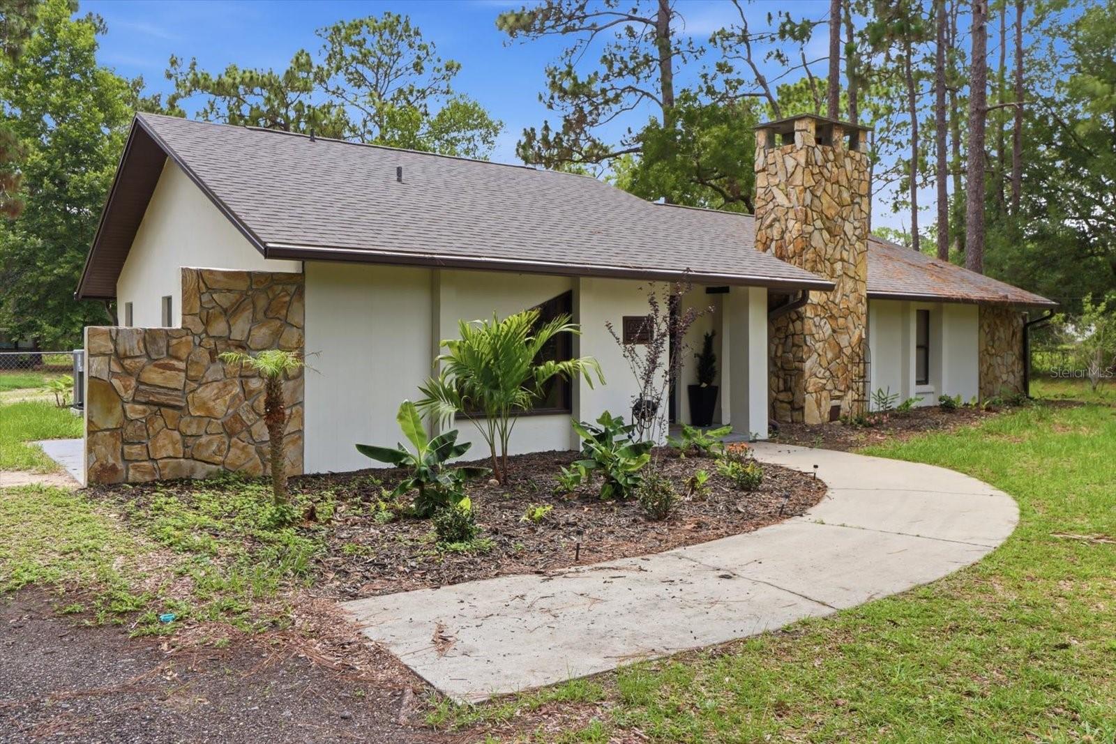 Welcome to this beautifully updated 3-bedroom, 2-bath home set on just over 5 private acres in the heart of Homosassa. Surrounded by mature trees and natural Florida landscape, this property offers space, privacy, and a peaceful rural setting while still being conveniently located near local amenities, shopping, dining, and the Gulf Coast’s renowned springs, boating, and fishing destinations.

Inside, the home features a desirable split-bedroom floor plan and an open-concept design that enhances flow and functionality. The spacious living room showcases a stunning floor-to-ceiling stone fireplace, creating a warm and inviting focal point. The beautifully updated kitchen is equipped with granite countertops, white shaker cabinetry, tile backsplash, stainless steel range hood, great storage space, and a breakfast bar that seamlessly connects to the dining area and breakfast nook.

The dining area features a charming wood accent wall and overlooks the backyard, with sliding glass doors leading to a screened-in porch for year-round indoor-outdoor living. The breakfast nook also provides additional casual dining while enjoying backyard views.

The primary suite includes a walk-in closet and a private ensuite bath, while the additional bedrooms are nicely sized and well-appointed. Both bathrooms have been thoughtfully updated. No carpet throughout—tile flooring runs seamlessly across the entire home for easy maintenance and durability.

Additional features include a 2-car carport, a large outbuilding ideal for storage, workshop, or equipment, and expansive acreage offering endless possibilities for gardening, recreation, or future improvements. This property combines comfort, functionality, and acreage living in one exceptional Homosassa retreat.