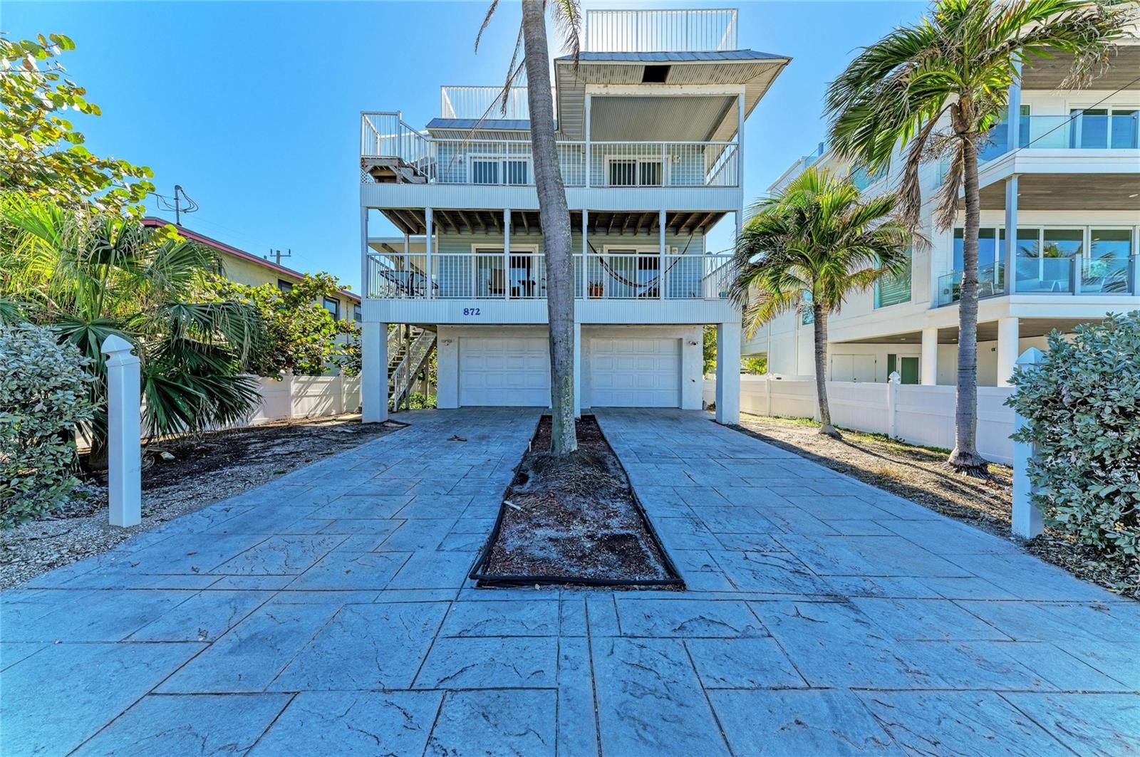 BEAUTIFUL WATER VIEWS. This four-bedroom, two-bath stilt home with a two-car garage offers magnificent, expansive views of Tampa Bay from every level. Designed to capture the beauty of its surroundings, the home features impact-rated windows and sliding glass doors throughout, complemented by stylish plantation shutters. Tile floors flow throughout both living levels and bedrooms. The first level boasts a spacious living and dining room combination alongside an open kitchen complete with granite countertops, stainless steel appliances, wood cabinetry, and an island cooktop—perfect for entertaining. This level also includes a guest bedroom and a full bathroom with a walk-in shower. On the second level, the primary suite offers a large walk-in closet and an en suite bath with a walk-in shower. Two additional bedrooms are located down the hall, along with a convenient inside laundry closet housing the washer and dryer. Both guest bedrooms enjoy stunning blue water views of Tampa Bay. The true money shot awaits on the third-level rooftop deck, where panoramic views stretch all the way around Anna Maria —the perfect setting for sunrise coffee or sunset gatherings. The spacious backyard provides ample room for a pool, and with some updating, this property could truly shine and reach its full potential.