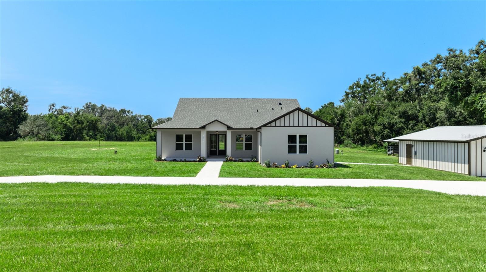 One or more photo(s) has been virtually staged. Modern farmhouse on 7.69 secluded acres in San Antonio, FL. 2,522 sq ft with open floor plan, quartz counters, and large flex room for office/gym/playroom or guest space. Property is ideal for horses, livestock, gardening, pets, all your homestead plans. Features a large, enclosed pole barn plus a second open pole barn with stalls. Quiet setting.  No HOA.  Minutes to I-75 and SR 52. Space, privacy, and convenience all in one.