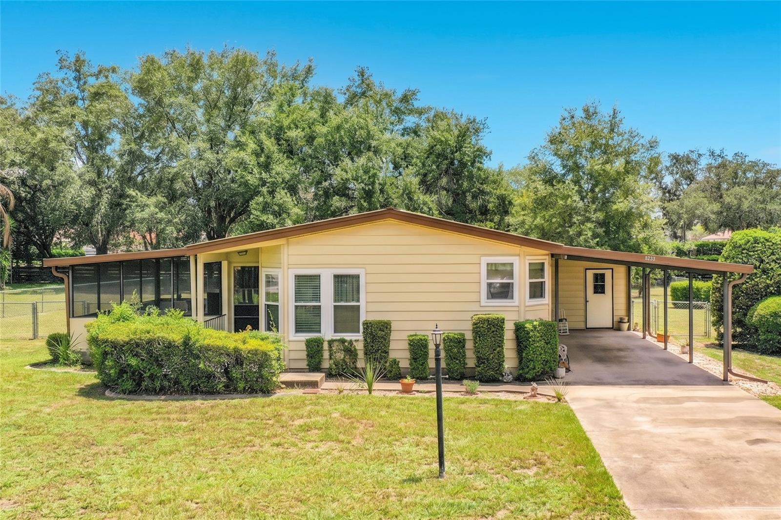 Welcome to Your Happy Place! Exceptionally well-maintained 2 Bedroom, 2 Bath Palm Harbor Manufactured Home with 1,430 Sq. Ft. Of Living Area and a Fully Screen Enclosed (20x12) Sun-Porch and Fenced Back Yard sitting on a Gorgeous 1/2 Acre lot that you Own! Centrally Located in the Heart of Lady Lake in Oakland Hills, a Quiet, All-Ages, Family Friendly Community, just 5 minutes from Spanish Springs Plaza in The Villages! This lovely home boasts a Large Formal Living and Dining Room with built-in cabinetry, Spacious Kitchen, Breakfast Nook, Large Primary Bedroom with walk-in closet and En-suite Bathroom, Roomy Guest Bedroom and Guest Bathroom, Convenient Inside Laundry Suite includes a wet sink, built-in desk area and cabinetry adding to this home's charm and versatility. Numerous Key features include Large Fully Enclosed (20x12) Screened Side Porch, Double-Pane Windows, Drywall, Ceiling Fans, Metal Roof, Newer 200 AMP Electric Service Panel, 3-Ton 14 Seer Bryant A/C (2021), Large Covered Carport (33x12), Oversized attached Storage Room could also be used as a Workshop (15X12) -- plus, Low Property Taxes, No CDD fees, No Lot Rent, No HOA and No Bond all less than 2 miles of The Villages, shopping, doctor's offices and medical facilities. Call to Schedule your Showing Appointment Today!