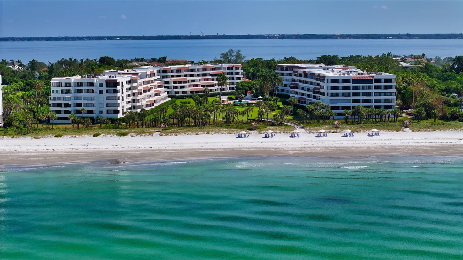 Step into this highly desirable corner residence featuring three bedrooms, three full baths, and an expansive 36’ x 11’ sunroom at The Players Club. You’ll immediately be drawn to the impressive 31-foot balcony, offering sweeping views of the resort-style pool, lush, landscaped grounds, and breathtaking sunsets over the Gulf of Mexico. The outdoor space is perfect for alfresco dining, entertaining friends, or simply enjoying the tranquil Gulf breezes.  Inside, the sun-filled kitchen is thoughtfully designed with custom cabinetry and a built-in breakfast table that expands both workspace and storage. It flows seamlessly into the main living and dining areas, creating a warm and open environment for entertaining or daily living. Just off the kitchen, elegant French doors open to a generous multipurpose sunroom that can serve as a home office, reading retreat, casual lounge, or even a fourth bedroom for guests.  The owner’s suite provides a private sanctuary with a spa-inspired bathroom featuring a soaking tub, separate glass-enclosed shower, dual vanities, and a spacious walk-in closet. The second bedroom functions as a true secondary master, complete with dual sinks, a full vanity, and a fitted walk-in closet, offering comfort and privacy for family or visitors. A third bedroom adds flexibility for guests, workspace, or hobbies.  A unique feature of this residence is the private garage, offering rare security and convenience for residents, plus an additional covered parking space underneath the building for extra guest or secondary vehicle use.  Set on 11 acres of beachfront with 560 feet of Gulf frontage, The Players Club offers abundant green space, four Har-Tru tennis courts, a 70-foot heated saltwater pool, spa, fitness center, renovated clubhouse with catering kitchen, outdoor grilling areas, putting green, on-site management, and fully funded reserves. Just minutes from St. Armands Circle, downtown Longboat Key, and Longboat Key Club, with championship golf, premier tennis, and a deep-water marina, this corner residence blends privacy, convenience, and resort-style coastal living. Units with this versatile layout and resort-ready features are highly sought after. Offered partially furnished.  Seller is willing to discuss a subsidy on the quarterly condominium fee for reserve increase over the next two years!