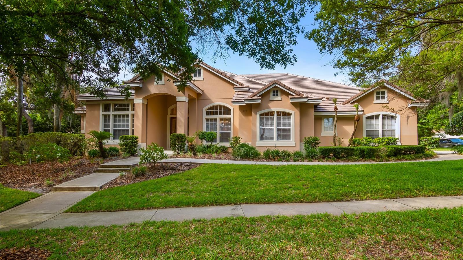 In one of Lake Mary’s gated communities, this elegant custom pool home in Heathrow is now offered at a remarkable new price, presenting an exceptional opportunity to enjoy refined living in a sought-after setting. On a desirable corner homesite within the Stonebridge section of the community, this impressive single-story residence offers more than 3,500 square feet of thoughtfully designed living space that blends comfort, style and effortless indoor outdoor living. A gracious foyer welcomes you inside where beautifully proportioned formal living and dining rooms create a warm first impression and provide the ideal setting for gatherings and celebrations. Just beyond, the heart of the home opens into a spacious family room with a gas fireplace and custom built-ins that flow naturally into the well-appointed kitchen and casual dining area. The kitchen features a central cooktop island, stainless steel appliances, 42-inch cabinetry, generous counter space and a breakfast bar that invites conversation while meals are prepared. A sunlit breakfast nook is framed by a seamless window that looks out across the sparkling pool and private backyard, bringing natural light and tranquil views into the living spaces. The flexible floor plan offers four bedrooms along with a dedicated office that includes a closet and convenient access to a nearby half bath, making it ideal as a fifth bedroom if desired. The three-way split design provides privacy and comfort for family and guests alike. The primary suite is a peaceful retreat featuring its sitting area, direct access to the pool, two walk-in closets, a linen closet, and a spacious en-suite bath complete with a jetted soaking tub, walk-in shower, dual granite vanities and private water closet. Go outside to a beautifully designed screened lanai where the pool and spa create a resort-style atmosphere. The covered entertaining space and outdoor kitchen area make it easy to host gatherings or simply relax poolside while enjoying the lush mature landscaping that surrounds the private rear yard. Peace of mind comes with a new tile roof installed in November 2025 along with several additional updates completed in 2025, including a freshly painted pool deck and front entrance walkway, new exterior cameras with security lighting, neutral carpeting, an updated water heater, and new pool and spa lighting. A spacious laundry room with extensive storage and an oversized three-car garage add everyday practicality to this beautifully maintained home. Life in Heathrow offers an exceptional lifestyle. Residents enjoy 24-hour manned gated security, tree-lined streets with sidewalks, and access to Sawyer Lake Park featuring playgrounds, ball fields, picnic areas and lighted basketball courts. Optional memberships are available at Heathrow Legacy Country Club where residents can experience two championship golf courses with 36 holes, tennis facilities, resort-style pools, dual clubhouses and a newly updated athletic center. All this is just minutes from Lake Mary’s premier shopping and dining, highly rated Seminole County schools, and convenient access to major highways along with miles of scenic recreational, running and biking trails. This is a rare opportunity to own a beautifully updated custom home in one of Central Florida’s desirable communities while enjoying the relaxed elegance and resort-inspired lifestyle that Heathrow is known for.