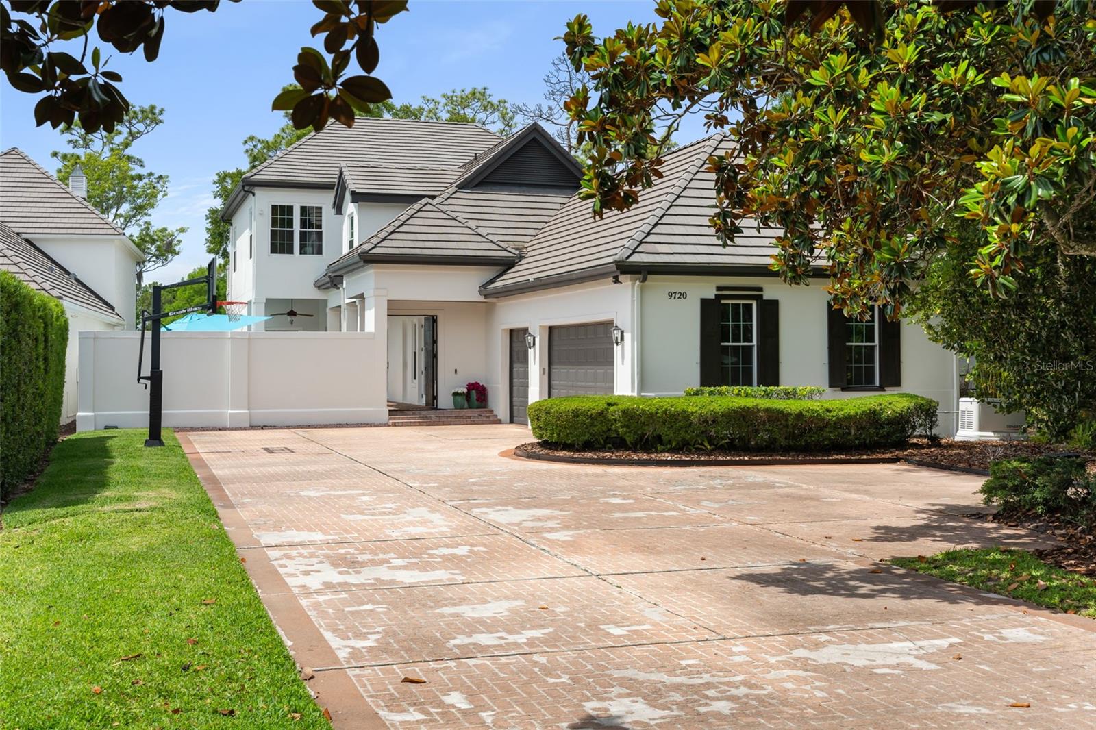 Welcome to 9720 Covent Garden Drive, a truly remarkable estate nestled within the gates of Lake Nona Golf & Country Club, where architecture, privacy, and nature exist in perfect harmony. Hidden behind a winding 300-foot private driveway, this beautifully renovated golf-front residence offers an extraordinary lifestyle surrounded by breathtaking water and championship golf course views. Centered around a stunning heated saltwater courtyard pool, this exceptional residence seamlessly blends indoor and outdoor living while creating a private resort-like setting unlike anything else in the community. From the moment you enter, soaring ceilings, imported wood beam accents, and a dramatic gas fireplace create a warm yet sophisticated atmosphere. The open-concept floor plan is flooded with natural light and framed by picturesque views of the golf course, water, and professionally landscaped grounds. At the heart of the home is a completely reimagined chef's kitchen, renovated in 2023 and featuring custom cabinetry, premium finishes, a Wolf commercial-grade gas range and oven, expansive island seating, and an impressive butler's pantry. French doors from both the kitchen and living areas open to a spacious 39-foot screened lanai, creating a seamless connection between the interior living spaces and the beautiful outdoor environment. The luxurious primary suite serves as a private retreat, offering sweeping golf and water views, an oversized 10' x 15' custom dressing room with California Closet built-ins, a private coffee bar, and direct access to both screened and open-air balconies overlooking the lush landscape below. Brick paver pathways wind through mature gardens and lead toward the golf course and water, creating a tranquil setting rarely found within the community.