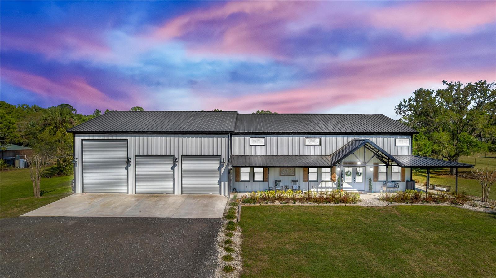 LISTED $123K BELOW APPRAISED VALUE!! Welcome to your ULTIMATE modern farmhouse dream—where luxury meets wide-open living on 5 PRISTINE ACRES! This newly built barndominium is more than a home; it’s a lifestyle. This one-of-a-kind 3 bedroom, 3 bathroom PLUS an office offers the perfect blend of luxury, functionality, and open country living. With 2,250 square feet of beautifully finished living space complemented by a 2,000 square feet shop with an ADDITIONAL 2,250 square feet UNFINISHED upstairs, this property offers incredible flexibility for future expansion while still delivering high-end custom features throughout. Arrive through the stunning gated entrance and experience the perfect blend of privacy and functionality, with 3 fully fenced acres ideal for livestock and country living at its finest. Step through the double beautiful French glass doors into a thoughtfully designed home that immediately impresses. The kitchen is truly the heart of the home, featuring an impressive 8'x8' island designed for gathering and entertaining. Outfitted with quartz countertops, soft-close cabinetry, and exceptional storage with additional cabinetry on both sides of the island, this space blends beauty with functionality. Enjoy high-end conveniences including a custom hood, built-in drink fridge, microwave drawer, farmhouse sink, pot filler, and a custom-built pantry offering abundant storage. The main living area showcases a warm and inviting atmosphere with a striking electric fireplace set against a beautiful shiplap accent wall featuring floating shelves. Leading to the laundry room, you will find a custom glass barn door, adding both elegance and continuity to the home’s modern farmhouse design. The laundry room features built-in hampers, custom cabinetry, and a farmhouse sink. The office is equally impressive, highlighted by custom glass barn doors, creating a stylish and private workspace. The primary suite serves as a private retreat with a spa-inspired bathroom featuring dual vanities, a floating soaking tub, mirrors with built-in lighting, a spacious 4x6 walk-in shower with bench seating, and a custom-designed closet. Step outside and discover an entertainer’s paradise with over 1,700 square feet of porch space. Enjoy a bar-style setup with seating, a dedicated cook space, plus a sink and refrigerator. Unwind in the oversized hot tub or gather around the firepit under the stars. For those needing space to work or play, the property includes a massive 2,000 sq ft shop with drive-thru capability, a 12x14 garage door, additional 10x10 doors, and dual entry access. A 50-amp RV hookup and a 24x30 detached storage shed add versatility. Rarely does a property combine such craftsmanship with this much room to grow. This is a rare opportunity to own a turnkey estate offering both the peace of the country and the architectural prestige of a designer's masterpiece. Located within a small, private HOA with exclusive access to a private boat ramp on the St. Johns River—perfect for enjoying Florida living at its finest. Discover the perfect balance of grit and grace—schedule your private showing today! Property may be under audio and visual surveillance.