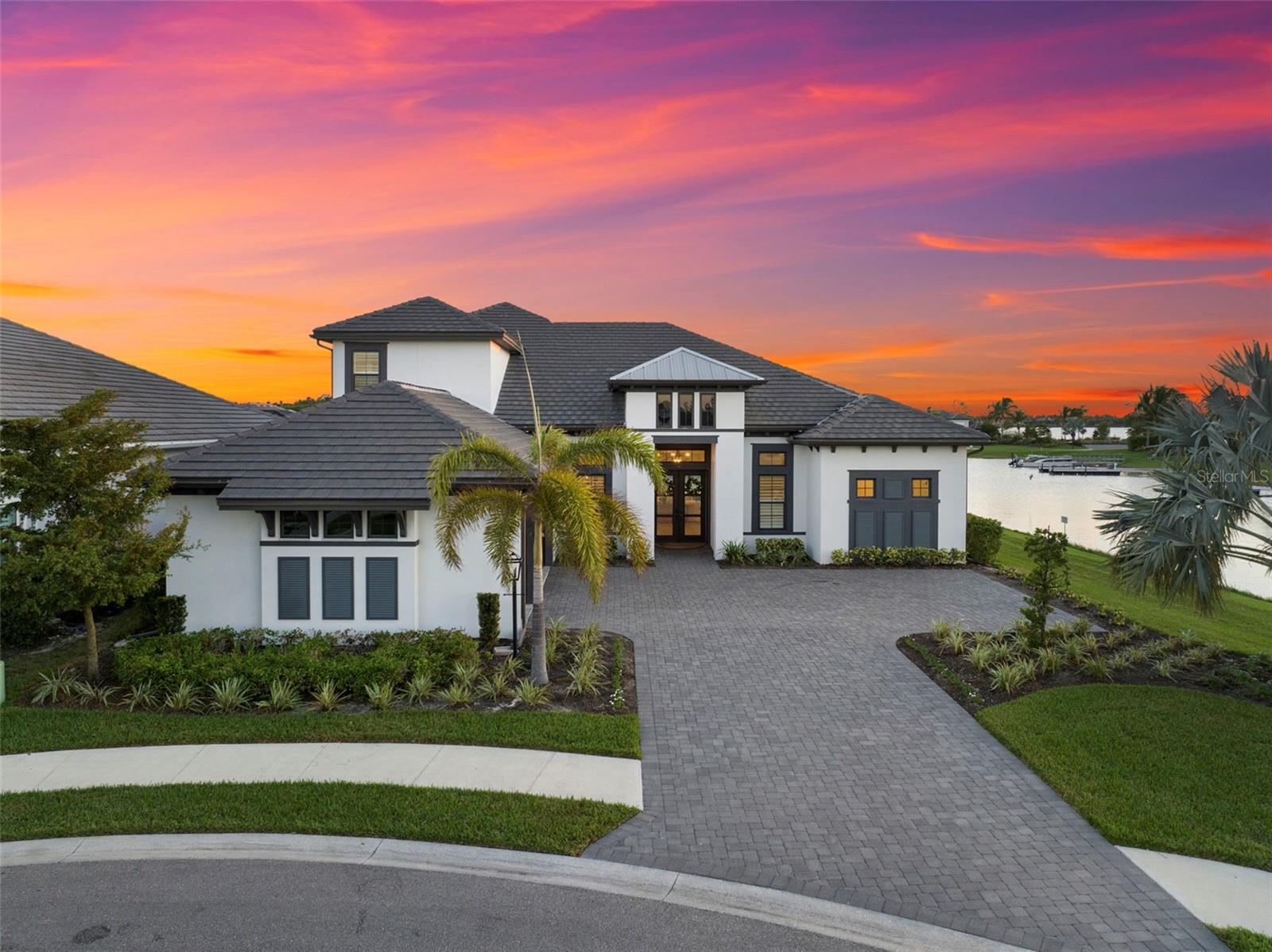 Under contract-accepting backup offers. Every detail of this lakefront residence was designed to inspire — a rare opportunity to own one of Esplanade Lake Club’s most extraordinary homes. Perfectly positioned on a Southern-facing cul-de-sac lot, this custom-designed estate offers nearly 5,000 square feet of living space, ultimate privacy, and panoramic lake views. With a private dock and expansive outdoor living, it’s a home that defines resort-style living — where every space feels as comfortable as it is beautiful. Classy yet inviting, this residence blends elegance with comfort and livability. The open-concept floor plan features 5 bedrooms plus home office/den, 4 full baths, 2 half baths, and a 3-car garage. A grand great room anchors the home with custom ceiling treatments, a natural gas fireplace, and serene water views. The first-floor primary suite provides a peaceful retreat with spa-inspired ensuite bath and generous walk in closets. The gourmet kitchen is a chef’s dream with GE Café appliances, quartz countertops, a reverse-osmosis water system, and a spacious walk-in pantry. Upstairs, a versatile bonus room with kitchenette and a guest suite with custom built-ins create the perfect space for family or guests. Step outside to your private lakeside oasis — a heated custom pool with infinity-edge spa, sun shelf, and putting green all overlooking tranquil waters. Entertaining is effortless with a full outdoor kitchen featuring Blaze grill, Summerset pizza oven, refrigerator, and cypress wood ceiling with electric roll-down screens. Additional features include impact-resistant windows and doors, a 26kW Generac Guardian Natural Gas generator, and meticulous designer details throughout. Furniture package is negotiable. Located within Esplanade Lake Club, a 352-acre gated lakefront community on Lake Como just on the Estero border, residents enjoy premier amenities including a lakefront beach, Bahama Bar & Grille, fitness center, tennis, pickleball, bocce, dog park, and more. All within minutes of RSW Airport, Gulf Coast Town Center, and world-class shopping and dining.  Modern design. Panoramic water views. Unmatched privacy. This is Esplanade Lake Club living at its finest.
