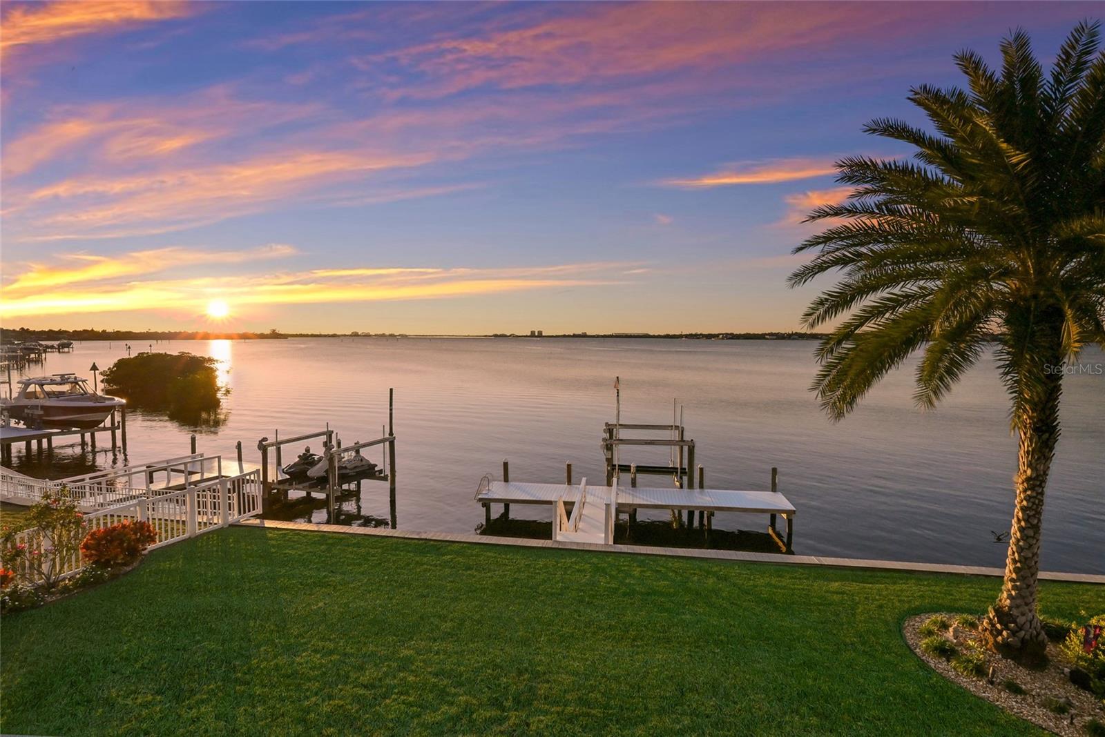 Welcome to The Reserve at Harbour Walk, an exclusive enclave of custom residences offering direct Gulf access within the privacy of a double-gated waterfront community. This exceptionally rare, former model home is positioned on an oversized direct waterfront lot, delivering an unparalleled boating lifestyle with open water views and sailboat access. The home’s striking coastal contemporary architecture is highlighted by refined metal roof accents, decorative flat tile roofing, a paver driveway, IMPACT WINDOWS/DOORS, and impeccably curated luxury landscaping—setting the tone for sophisticated waterfront living. Upon entering through elegant glass doors, you are immediately captivated by expansive water views and a modern, designer-curated interior. Inside, the residence showcases upgraded flooring, soaring 12-foot ceilings, custom trim work, extensive built-ins, and a full security system. The primary suite is a private retreat, featuring custom-designed closets, a tranquil sitting area with an aquarium window overlooking the water, and a spa-inspired primary bath designed for ultimate relaxation. A stunning glass-enclosed wine room with bespoke detailing adds a dramatic focal point for entertaining. The outdoor living spaces are nothing short of extraordinary, offering breathtaking views of the Manatee River and direct, deep-water access to the Gulf. The custom-designed pool and spa serve as a true showpiece, complete with a newer pool cage featuring a retractable panoramic screen wall, ambient lighting, and an expansive infinity spa. Adjacent, a fully equipped outdoor kitchen and dining area create the perfect setting for elevated coastal entertaining. For boating enthusiasts, the private dock is outfitted with a 16,000-pound boat lift with a recent 10-foot extension—allowing you to arrive home by water with ease, without the need for marina or dry dock storage. Recent enhancements include a WHOLE-HOUSE GENERATOR, helical anchors beneath the foundation for added security and stabilization, elevated pool equipment, built-in garage cabinetry with an electric lift providing access to generous attic storage, enhanced landscape lighting, new designer balcony tile, window shutters, and electric blinds. Professionally decorated and thoughtfully designed, this former model home exemplifies today’s upscale Florida waterfront lifestyle. This is a rare opportunity to own a direct open-water residence in one of the area’s most coveted gated boating communities.