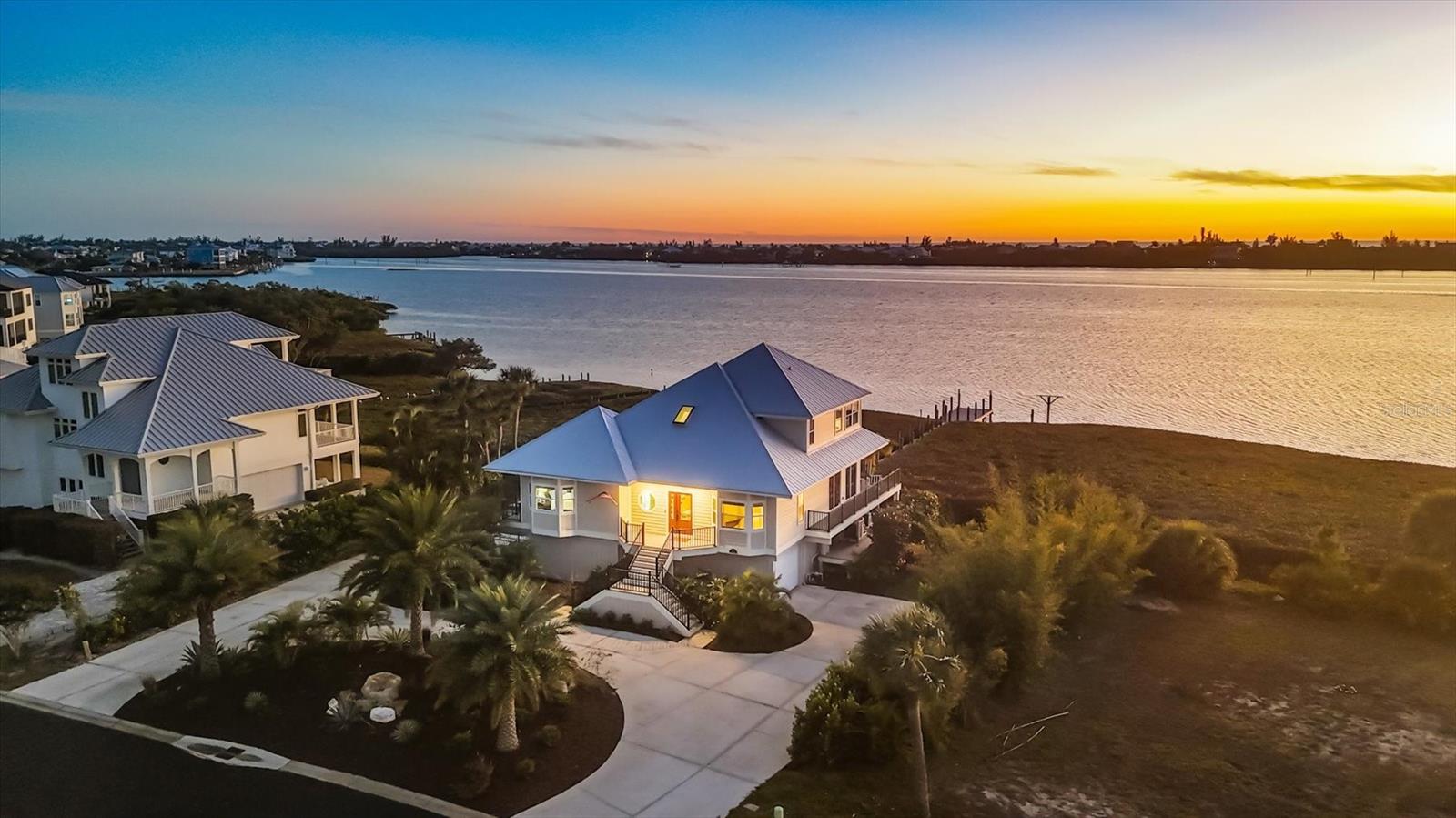 One or more photo(s) has been virtually staged. Spectacular Southwest Florida sunsets take center stage at this rare waterfront retreat offering 127 feet of direct Intracoastal Waterway frontage on over half an acre within the exclusive, gated enclave of Eagle Preserve Estates. Perfectly positioned between the fairways of Lemon Bay Golf Club and the shimmering waters of Lemon Bay, this custom contemporary elevated residence captures breathtaking evening skies from nearly every vantage point.
A beautifully landscaped approach leads to a striking entry, opening to immediate water views and a light-filled interior where wood flooring and open living spaces are designed for refined yet relaxed coastal living. The 3-bedroom, 3.5-bath home features thoughtfully curated finishes that create a warm yet sophisticated atmosphere. The kitchen blends elegance and functionality with quartz countertops, stainless steel appliances, and seamless flow into living and dining areas, ideal for both entertaining and everyday ease. An enclosed Florida room with soaring ceilings and sliding doors invites the outdoors in, offering a peaceful space to unwind while overlooking the water.
The private upper-level owner’s suite is a true sanctuary. Opening to a glass slider-filled private balcony showcasing stunning Southwest Florida sunsets over the water.  Complete with dual walk-in closets, mini bar and a spa-inspired bath with dual vanities, quartz countertops, a large shower and a soaking tub. The main level features two guest bedrooms, one with a large en-suite bathroom and direct access to the pool area, generous closet space, and abundant natural light.
Outdoors, a fenced waterfront oasis awaits, with a heated pool & spa, expansive decking, and a private, maintenance-free dock with water & electric, providing direct access to the Intracoastal Waterway leading to the Gulf. Explore the stunning water offering world-class fishing, boating, kayaking, paddleboarding, or just a relaxing day sitting on your dock fishing.  Hop on your golf cart and you are ready for a round of golf. With each evening leading to skies painted in gold and crimson. Need a place for the toys, an oversized two-car garage and lower-level flex rooms offer versatility and abundant storage.
Recent high-value upgrades provide peace of mind, including a metal roof (2022), water heater (2023), Hardie® Plank siding (2024), Trex PVC decking (2024), new front door (2024), and two new heat pumps (2024).
Located just minutes from the beaches, marinas, dining, Boca Grande and the coastal charm of Englewood and Manasota Key, this exceptional residence offers a lifestyle where sunsets, water, golf, and privacy converge in effortless Southwest Florida elegance.
Golf Membership Fees are Optional