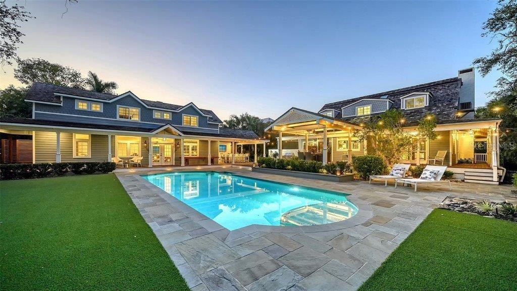 Welcome to this rarely available Cape Cod–style residence, comprised of a masterfully renovated main house and separate luxe guest house poised on an expansive 20,000 sq. ft. lot in Sarasota’s prestigious Cherokee Park. Elevated 23 feet above sea level and nestled on a wide, tree-lined street in the coveted West of Trail district—within the top-rated Southside school zone—this 4-bedroom, 3 full/2 half bath +office private compound blends timeless architecture with designer-curated sophistication. A stately front porch framed by lush landscaping and classic brick walkway introduces the home with understated grandeur. Handcrafted, glass-inlaid iron double doors open to a refined foyer where natural light, elegant millwork, and soaring 10-foot ceilings set the tone for the bespoke interiors beyond. Inside, original hardwood floors, designer lighting by Arteriors, Eichholtz, and Kelly Wearstler, and high-end finishes selected by Chelsea Dunbar of Blu Interiors create a sense of warmth and refinement throughout. The quartz-clad chef’s kitchen is as functional as it is beautiful, featuring a Wolf natural gas range, KitchenAid French-door refrigerator, ample pantry space, and custom cabinetry—perfectly suited for both intimate dining and entertaining. Anchored by a wood-burning fireplace, the main living and dining spaces flow seamlessly outdoors to an inviting Pennsylvania bluestone patio, low-maintenance Astroturf lawn, and wrap-around Brazilian teak deck—an idyllic setting for year-round enjoyment. The serene first floor primary suite is a private retreat showcasing three custom-designed walk-in closets and a spa-inspired bath with marble finishes, dual vanities, heated towel bar, and a zero-entry shower with body sprays. Ascend the custom staircase to find 2 tailored guest retreats with spa-like bath, each offering serene views and thoughtfully appointed details for ultimate comfort and privacy. Throughout the home, custom wallcoverings by Phillip Jeffries, Scalamandré, and Élitis add layers of texture and artistry, while upgraded systems—including a surround sound system, six climate zones, and multiple laundry areas—enhance everyday comfort. Resort-style living continues outdoors with a 9-foot-deep pool framed by classic Bevolo gas lanterns and an extraordinary luxury guest house built in 2016. This refined space includes an entertaining area with custom built-ins, full bar, refrigerator drawers, Scotsman icemaker, private guest suite, 1.5 baths, gym, and an outdoor teak shower. The fully equipped outdoor kitchen features a natural gas Lynx grill, XL Green Egg, quartzite prep counters, and a covered gazebo ideal for al fresco dining. All impact doors and windows, cedar shake roof, and Hardie Board siding add to the beauty and durability of the home. Completing this exceptional estate is an oversized 2.5-car detached garage and secure, fully fenced grounds with electric fence. Enjoy tree-lined streets with sidewalks and a true sense of community, all just a short stroll or golf cart ride to Southside Village where residents enjoy boutique shops, Morton’s Gourmet Market, cafés, and top-rated restaurants, and minutes from downtown Sarasota and Siesta Key Beach. This is refined Gulf Coast living—where timeless architecture meets effortless luxury in one of Sarasota’s most treasured neighborhoods.