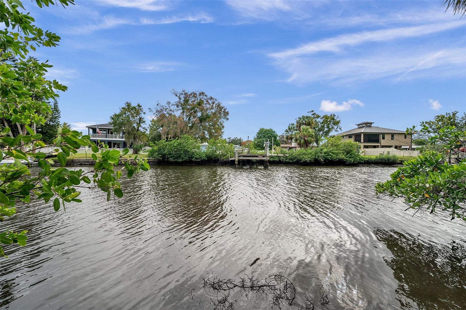 One or more photo(s) has been virtually staged. Coastal living in charming Tarpon Springs.  This lagoon front home is situated on a deep lot (approximately 76' x 170'), with access to the Gulf.  Features a split floor plan, spacious Florida Room and a Bonus/Family Room off the Kitchen.  Just outside, you'll find a generous sized SCREEN ENCLOSED PORCH, weather-protected OUTDOOR STORAGE space with BUILT-IN SHELVING and an extra large COVERED OUTDOOR PATIO, overlooking the calming waterways of Sunset Lagoon. The oversized GARAGE includes ample storage shelving, washer & dryer hook-ups, a utility door and an additional refrigerator.  Modern updates to this 2 bedroom, 2 bath, 1-car garage home include wood-look plank flooring throughout (no carpet!), neutral interior paint & exterior paint colors and updated light fixtures.  Washer and dryer connections are located inside the oversized garage.  This ideal location is an outdoor enthusiasts paradise - go fishing in your backyard, drop-in a canoe, paddleboard or kayak or take a quick bike ride to Howard Park, Sunset Beach or the historic Sponge Docks. Quiet neighborhood with NO HOA or deed restrictions.