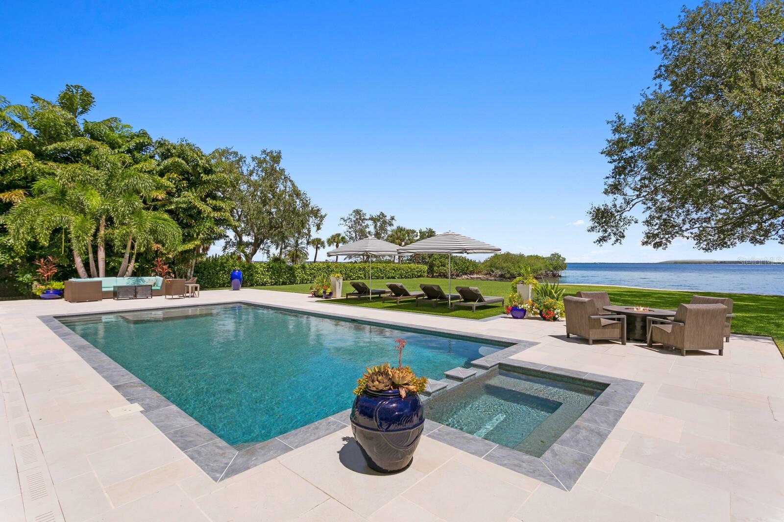 Introducing the perfect private coastal escape in the historic and scenic Ballast Point neighborhood of South Tampa. Be transported via a private road to a tranquil bayfront location surrounded by majestic oaks and inviting Old Florida charm. This estate property spans a FULL ACRE on the open bay and with a rarely found 150 ft. of water frontage. An award-winning coastal design, built by Sample Properties in 2018, welcomes you to refined finishes, dramatic designer appointments and superior outdoor living areas, with 5 bedrooms, 6.5 baths and over 5,000 square feet. Boasting magnificent views from almost every room, you are greeted by a double door entry to light-filled living spaces, great room with fireplace, dining room, warm hardwood floors and designer lighting, along with pecky cypress beam and wood accent ceilings. Sure to please the most discerning chef of the family, the custom kitchen delivers seamless design, center island and quartzite counters, custom cabinetry, integrated appliances (Sub-Zero/Wolf), 6-burner gas range and expansive walk-in pantry overlooking an informal dining/sitting area and water views beyond.  Additional first floor living spaces include a mud room, powder bath and office.  Upstairs, an impressive primary bedroom offers a private terrace, walk-in closet and spacious marble bath with dual vanities, dual water closets and soaking tub. Three additional ensuite bedrooms and laundry room complete the second living level. An intermediate level features a separate private guest/in-law suite offering a generous sitting area, bedroom, stunning bath and walk-in closet. The very best of this marvelous setting awaits outdoors with wide open water views, expansive covered terrace (blue marble), outdoor fireplace, dining area, outdoor kitchen, and pool bath. A heated pool/spa with custom cut limestone pool deck, plus waterfront Ipe deck complete the magazine worthy grounds. Exceptional exterior designed by Levell Design that includes custom railing, landscaping, pool deck, with no expense spared in the extraordinary marine-grade copper Aurora exterior landscape lighting system. Additional appointments include reinforced and recapped seawall 2020, separate cottage with storage and elevated living space (playroom, studio or home gym), along with an expanded 3-car garage. Convenient and walkable to the renowned Tampa Yacht Club, Bayshore Boulevard, Ballast Point park, this superior South Tampa estate delivers the ultimate in Florida Waterfront Living yet proximity to all that the City of Tampa has to offer.