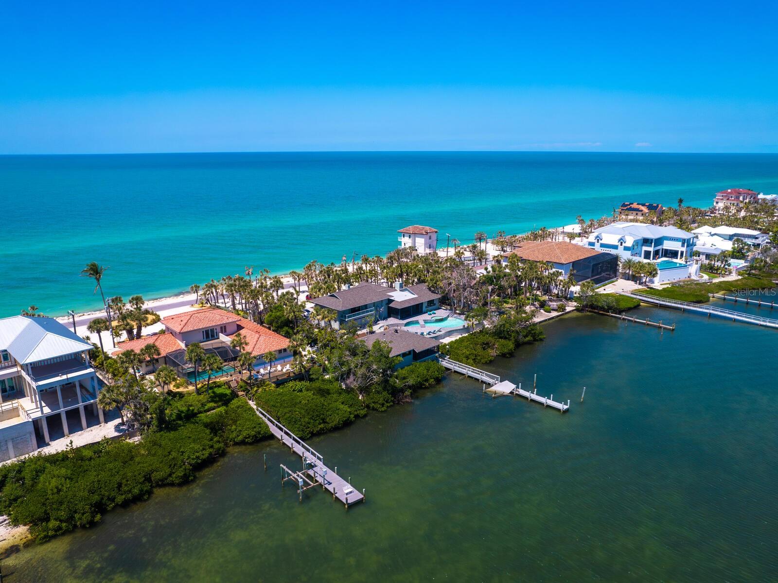 This captivating Gulf-to-Bay residence is the epitome of timeless coastal elegance. Begin your mornings on the lanai, coffee in hand, as the sun rises over the Intracoastal Waterway. Spend your days boating from the private bayside dock and your evenings on your stretch of sandy beach, where spectacular Gulf sunsets are a nightly ritual. Inside, expansive light-filled interiors frame breathtaking water views in nearly every room. The main living area enjoys bay and beach vistas, while a beachside family room and generously sized guest bedrooms easily accommodate king-sized furnishings. The kitchen is designed as a gathering place, complete with abundant beverage and wine refrigeration—ideal for effortless entertaining. The entire second level is devoted to a luxurious primary retreat, offering panoramic Gulf and bay views from a private beachside balcony and a bayside deck. The spa-inspired en-suite bath, finished in crisp coastal whites and blues, provides a tranquil setting with serene Gulf views. Designed for outdoor living, the backyard is a private tropical sanctuary featuring a large screened pool and spa, a covered stone lanai, expansive sun deck and an outdoor kitchen worthy of a Food Network showcase. Premium upgrades provide peace of mind, including a Kohler generator, new tile roof, hurricane-braced garage doors, impact-resistant windows and an automatic pool cover. On tranquil Casey Key, a quiet barrier island in South Sarasota, this exceptional home offers convenient access to world-class dining, shopping, golf, tennis, and the charm of downtown Venice and Sarasota. Whether arriving by private or commercial air, this is Florida living at its most refined.