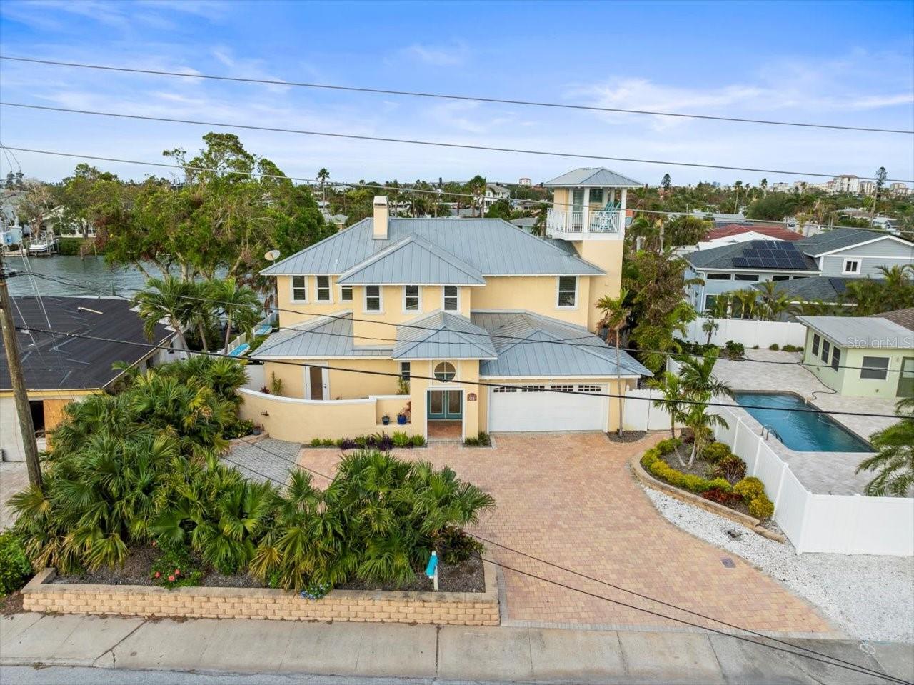 Here is the beach home you've been dreaming about! No damage from Hurricane Helene, and minor wind blown damage from Hurricane Milton. Elevation certificate available upon request states, "the top of the reference level floor from the selected diagram is at an elevation of 11.04 feet...." This Pass-a-Grille/Vina Del Mar boater’s paradise boasts three bedrooms, plus office (currently used as a 4th bedroom) and loft space, with 4 full baths, where you'll have plenty of room for family and guests to all have their own private spaces. This home checks all the boxes - waterfront, dock with lift, saltwater pool, hot tub, and fully remodeled inside. Enjoy the amazing views from both inside, outside, and on multiple balconies, including a covered rooftop terrace. The inviting living space with soaring ceilings is open and spacious, and features a fireplace and engineered hardwood flooring. French doors open to let the breeze come in, as you step out to your private pool oasis. The chef in the family will appreciate the gorgeous kitchen featuring granite counters, stainless steel appliances, white shaker-style cabinets and a long breakfast bar. With four full bathrooms, there are options on both the first and second floors to have an ensuite bedroom. The large, primary suite is on the second floor, and features a fireplace, spacious walk-in closet, plantation shutters, private balcony overlooking the pool and waterfront, and an oversized shower with separate tub. All the furniture you see in the home is included in the sale. The location is incredibly special - nestled in the quaint Pass-a-Grille area of St Pete Beach, just a 5-minute walk and you will have your toes in the sand.  And, only minutes away from many charming shops and restaurants, as wells as the “Pink Palace”, The Don Cesar!  Do not miss your chance to own a piece of paradise, call today for your appointment to see this jewel!