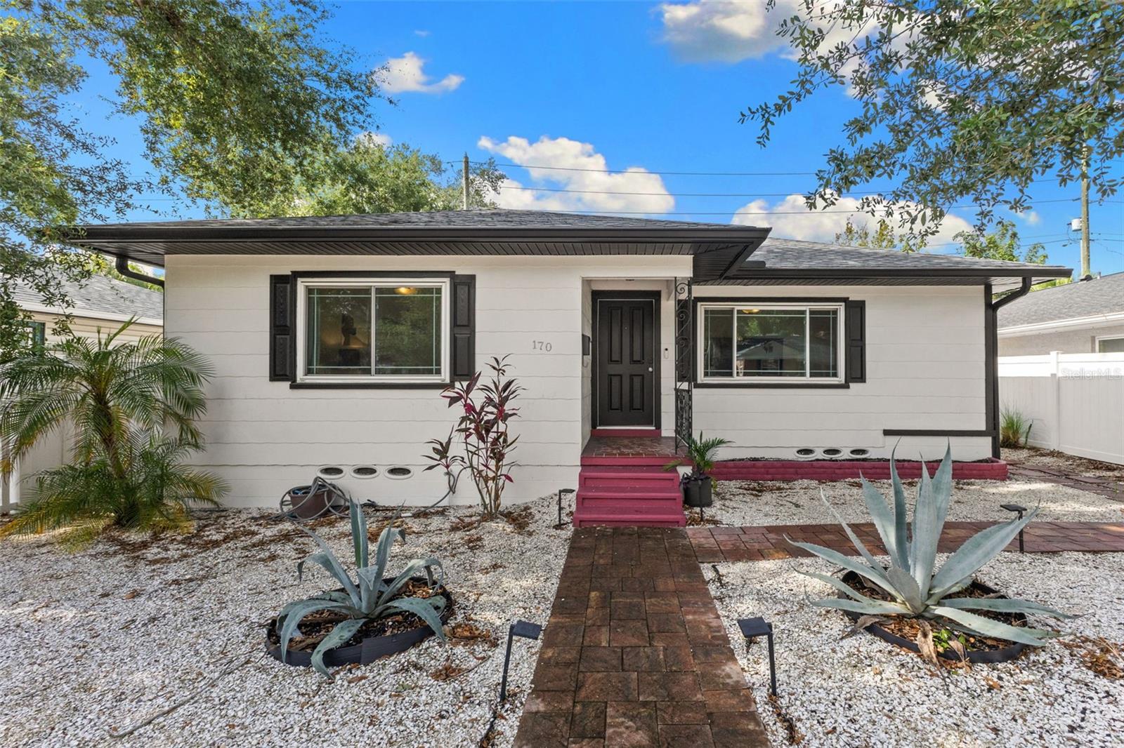 Welcome to one of St. Petersburg's most beloved neighborhoods—Historic Old Northeast. Just a few blocks from the sparkling waters of Coffee Pot Bayou, this charming 1950s bungalow blends timeless character with thoughtful modern updates in one of the city's most sought-after locations. A vinyl white-picket fence and manicured front yard welcome you home before you step inside. Original hardwood floors, beautiful coved ceilings, and abundant natural light immediately showcase the warmth and craftsmanship that make homes of this era so special. The kitchen has been tastefully updated while preserving the home's personality. Granite countertops, stainless steel appliances (including a double oven), updated cabinetry, and classic black-and-white checkered tile flooring create a timeless space that feels both fresh and authentic to the home's mid-century roots. Just beyond the kitchen is a bright flex room filled with natural light, making the perfect home office, reading room, hobby space, playroom, or additional sitting area overlooking the backyard. Both bedrooms are generously sized and continue the home's inviting feel with beautifully maintained hardwood flooring and large windows that fill each room with sunshine throughout the day. The hall bathroom has classic hexagon tile and a combination shower and bathtub with subway tiled walls and a rolling glass door enclosure. The primary en suite bathroom has been tastefully renovated with modern tile, updated fixtures, and a walk-in shower. The attached one-car garage offers exceptional versatility. An electric vehicle charging station is already installed, making it ready for today's homeowner, while workshop enthusiasts will appreciate the convenient half bathroom with a toilet and large utility sink located directly inside the garage. Your washer and dryer are also located here. These features make it easy to convert the garage into additional living space if you wish to do so. Alley access leads to the garage and there are additional parking spaces next to the driveway providing room for guests. Step outside and discover a backyard designed for relaxing and entertaining. A durable PVC privacy fence surrounds the spacious yard, while an expansive paver patio offers the perfect setting for outdoor dining, grilling, and entertaining. This home has been meticulously maintained with significant improvements already completed, including double paned, hurricane impact windows (2015), a newer roof (2019), paid-off solar panels with battery backup (2019), hurricane impact front and rear doors (2020), AC condenser (2020), air handler and ductwork (2021), newer electrical panel (2021), and all cast-iron plumbing underneath the home has been changed to PVC (2023). Living in Historic Old Northeast means enjoying one of St. Petersburg's most walkable lifestyles. Coffee Pot Bayou, Crescent Lake Park, Sunken Gardens, the Coffee Pot boat ramp, protected bike lanes, and the shops, restaurants, and coffee houses along 4th Street North are all just a short stroll away. Downtown St. Petersburg, I-275, multiple airports, and the Gulf beaches are only minutes from your front door. Lovingly maintained and thoughtfully updated, this home offers the perfect balance of historic charm, modern convenience, and an unbeatable location. Come experience everything this Historic Old Northeast bungalow has to offer! *Floor plan and virtual tour available for this property