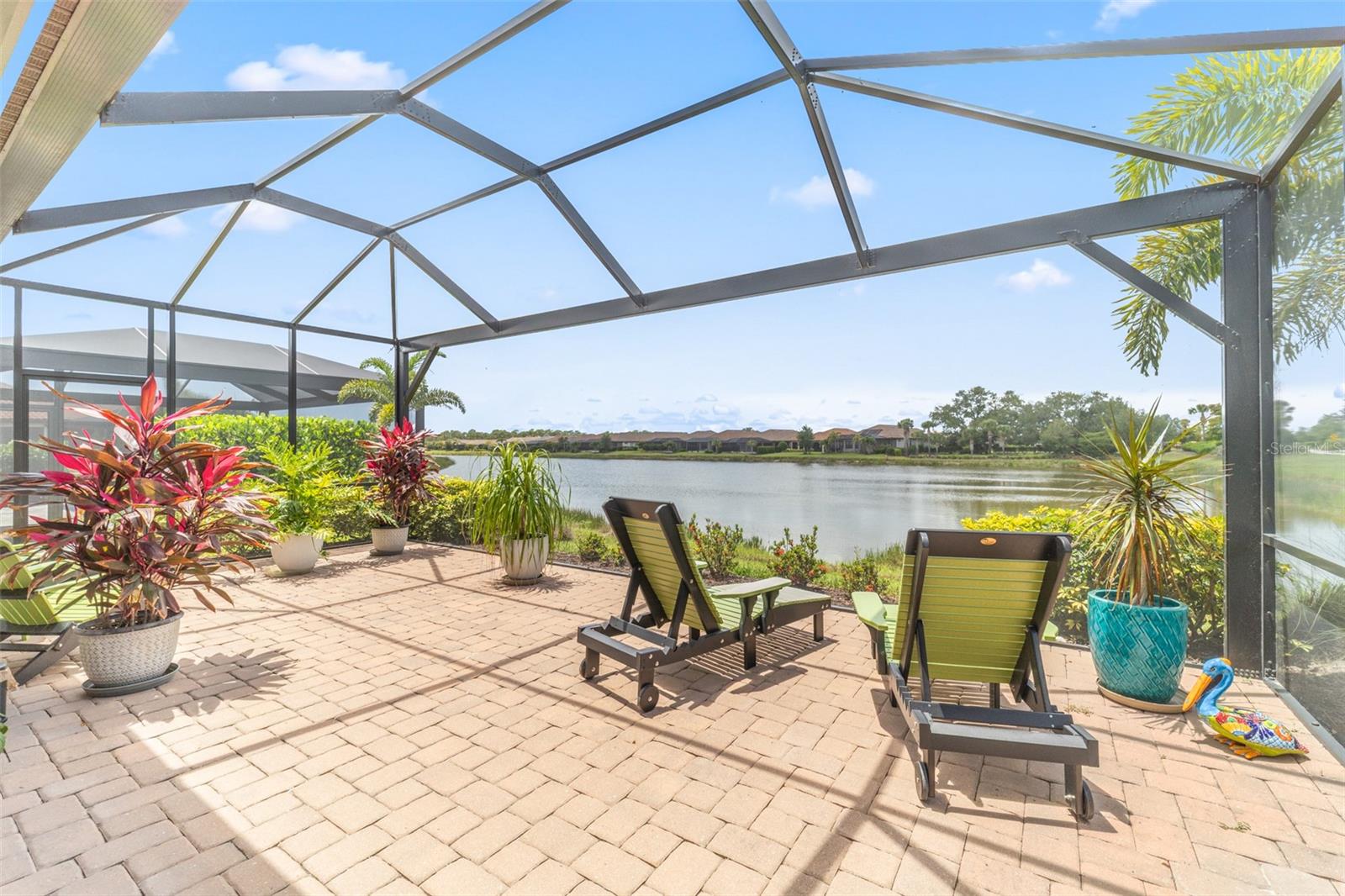 Welcome to the highly coveted Esplanade on Palmer Ranch, Sarasota’s premier gated community offering maintenance-free resort-style living. This impressive waterfront 3-bedroom plus den, 2-bathroom Arezzo model blends luxury with effortless functionality, complete with an extended two-car garage and enlarged lanai. Step inside to find an airy, open-concept design featuring high ceilings, coastal modern wood-look plank tile, crown molding, and impact-rated windows and sliders for absolute peace of mind. The chef's kitchen features premium Cambria stone countertops, a gas range, stainless steel appliances, a touchless faucet, and a reverse osmosis filtration system, flowing seamlessly into the main living and dining areas. The heart of the home opens to a private outdoor paradise. The enlarged lanai is completely enclosed by a panoramic screen cage with unobstructed lake views and equipped with remote-controlled storm shades. The spacious primary suite serves as a spa-inspired retreat with serene water views, large dual vanities, a frameless glass walk-in shower, and dual walk-in closets. Two additional bedrooms share a full bath, while the versatile den makes a perfect home office or gym. A dedicated laundry room offers gas or electric dryer hookups. Live like you are on vacation every day, just steps from all amenities: a resort-style pool, the Bahama Bar, a fitness center, sports courts, dog parks, and private access to the Legacy Trail. You are also just minutes from Siesta Key Beach, downtown Sarasota, Venice, and countless dining and shopping options. Experience ultimate Sarasota living in beautiful Esplanade on Palmer Ranch. Schedule your private showing today, you'll be glad you did!