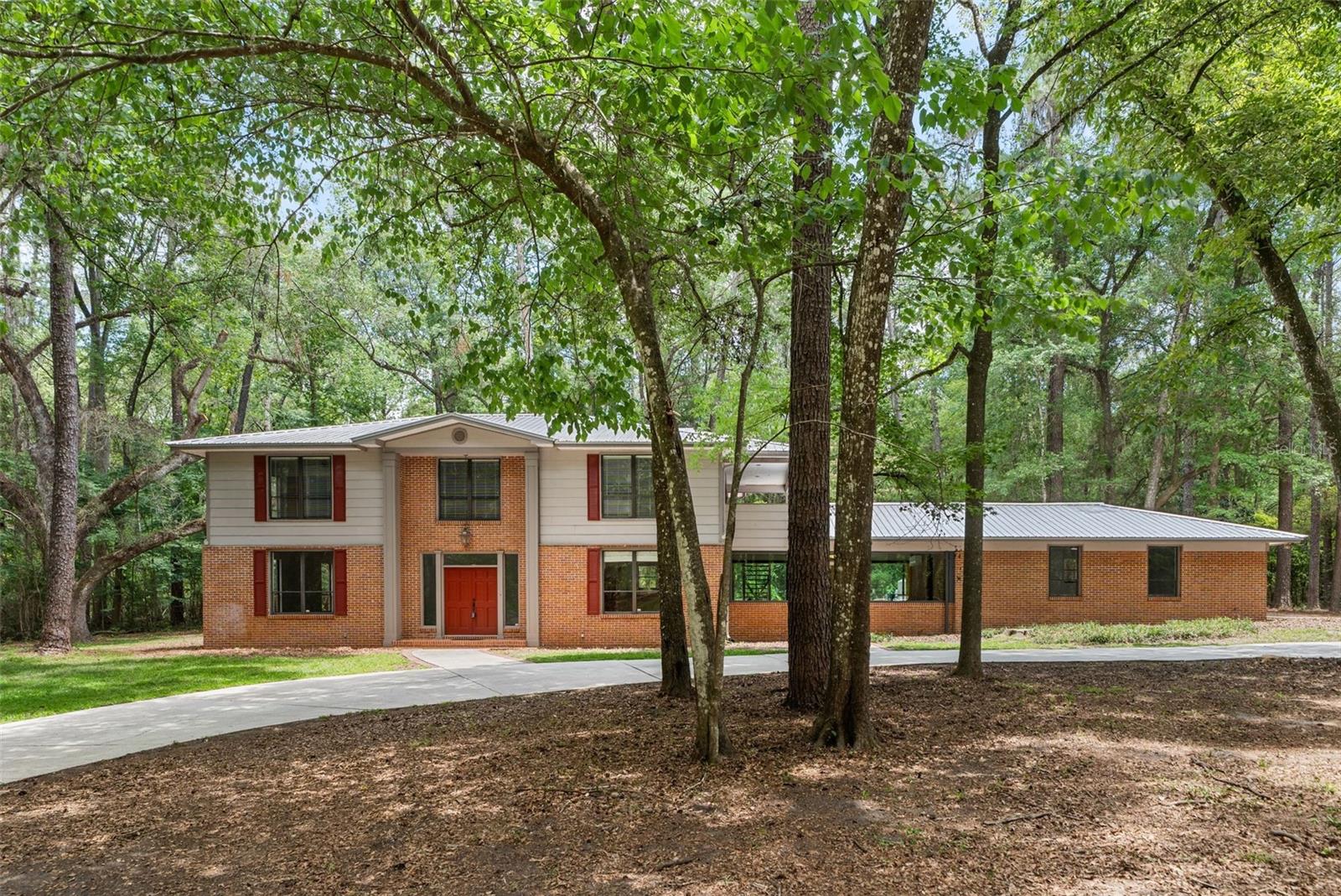 Nestled among 6.1 acres of peaceful wooded surroundings in highly desirable NW Gainesville, this private retreat offers a rare opportunity to enjoy the beauty of nature, space, and convenience in one remarkable setting. Approached by a graceful circular concrete driveway framed by mature trees, the property immediately evokes a sense of privacy, tranquility, and timeless North Florida charm.

Built in 1972, this spacious 4-bedroom, 2.5-bath home offers approximately 3,422 heated square feet with generous living areas and enduring character ready for its next chapter. Large windows and an expansive sunroom invite the outdoors in, overlooking the pool and tranquil wooded views beyond. Whether enjoying quiet mornings with coffee, gathering with family and friends, or simply unwinding in nature, the setting creates a calming and restorative atmosphere.

Several meaningful improvements have already been completed, including a new HVAC system installed in April 2026, a mini-split system added to the sunroom for year-round comfort, recent interior paint, exterior trim paint, and tree trimming to further enhance the property’s natural beauty and presentation. The property also features a metal roof, private well and septic, private pool, and expansive acreage offering flexibility, privacy, and room to roam. 

Tucked away in a peaceful natural setting, yet conveniently located near I-75, the University of Florida, UF Health, shopping, dining, and surrounding communities, this property offers a rare blend of privacy, accessibility, and possibility. Rich with character, warmth, and natural beauty, this special property offers the opportunity for its next owners to bring their own vision to life while enjoying the serenity, privacy, and timeless appeal of a true North Florida retreat.