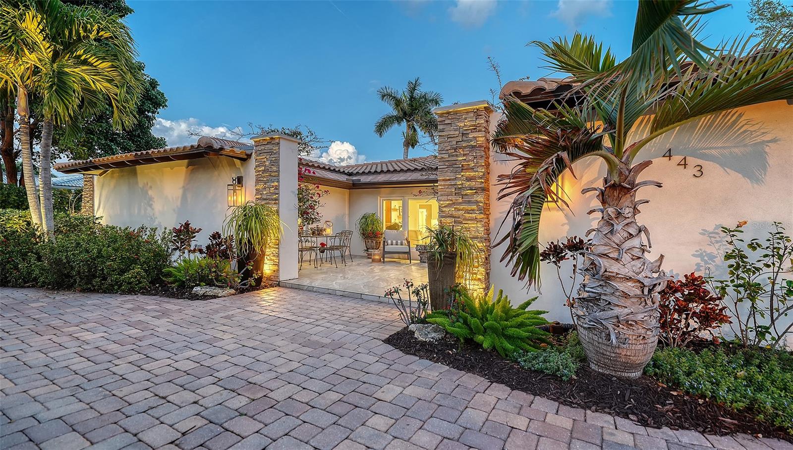 Poised on the coveted island of Bird Key, just across the graceful span of the John Ringling Causeway Bridge from downtown Sarasota, this striking Mid-Century modern garden home captures the timeless ease of coastal living. This beautifully designed one-level residence offers three bedrooms, three baths, and 2,676 square feet of thoughtfully arranged living space, where clean architectural lines meet warm, inviting finishes. A neutral palette, 18-inch porcelain tile flooring, and dramatic stone accent walls create a sophisticated yet relaxed atmosphere throughout the open floor plan. Multiple seating areas flow naturally from one space to the next, anchored by a charming wood-burning fireplace—perfect for intimate evenings or lively gatherings. A wall of sliding glass doors dissolves the boundary between indoors and out, opening to a private tropical retreat. The heated pool and expansive screened patio are framed by lush landscaping and a comfortable outdoor seating area designed for effortless entertaining, sunset cocktails, and relaxed Florida afternoons. At the heart of the home, the spacious kitchen invites both conversation and culinary creativity. A large island with granite countertops, elegant pendant lighting, stainless steel appliances, and a stylish backsplash makes it equally suited for casual breakfasts or hosting memorable dinners with friends and family. Peace of mind meets modern convenience with hurricane-impact windows and doors throughout the home. Arrival is equally impressive. A circular paver driveway welcomes guests, complemented by beautiful outdoor lighting and a charming courtyard that leads to the front entrance—an inviting prelude to the warmth within. This home is also pet friendly with a fenced back yard area to keep your pooches secure. The neighborhood offers many walking areas and the Bird Key Park, directly across from the Bird Key Guard House entrance, is a wonderful place to enjoy sunset views over Sarasota Bay. Perfectly positioned just moments from the new Bird Key Yacht Club under construction, the boutiques and dining of St. Armands Circle, and the pristine sands of Lido Beach, this residence offers the rare combination of island serenity and vibrant coastal lifestyle. A timeless retreat in one of Sarasota’s most desirable communities—where elegance, comfort, and the gentle Gulf breeze come together beautifully.