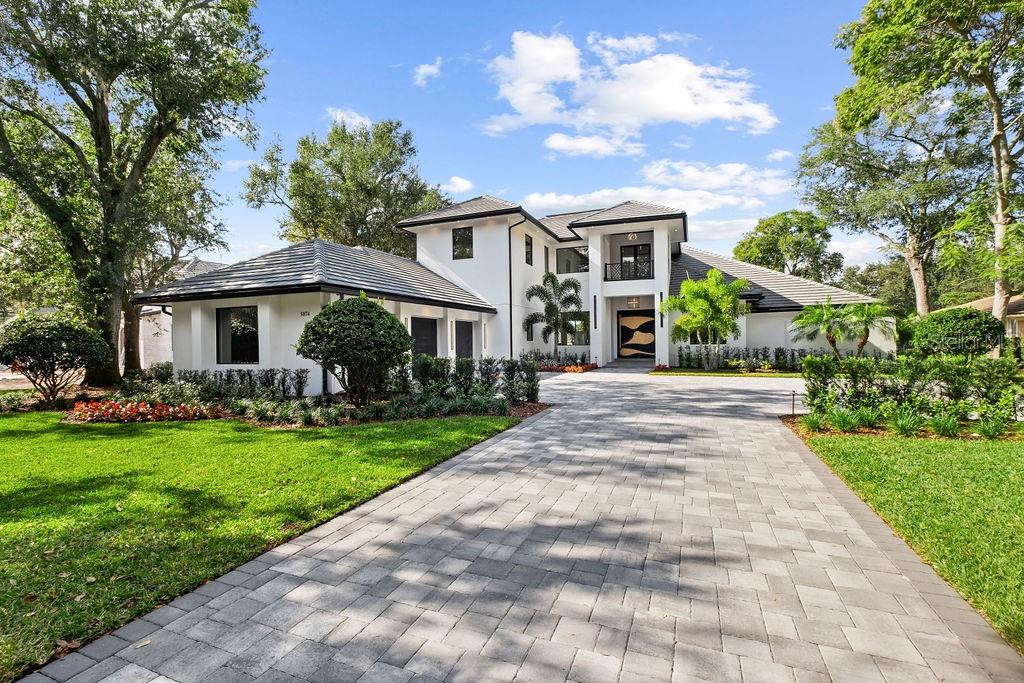 A masterfully reimagined golf-front estate, this residence offers an unparalleled standard of luxury within the acclaimed guard-gated community of Isleworth. Completely reimagined and expanded, the residence offers over 7,000 square feet of refined living space, including a 2,400+ square-foot second-story addition designed by acclaimed architect Mark Nasrallah. Situated on over half an acre, the two-story home features 5 bedrooms, 6.5 bathrooms, and a seamless blend of timeless modern design and resort-style living. A striking 10-foot custom pivot door welcomes you into light-filled interiors, where elegant European porcelain tile and expansive open living spaces create a bright, elevated ambiance. Designed for both entertaining and everyday living, the main living areas flow effortlessly through expansive sliding glass doors to a stunning outdoor retreat, complete with a fully retractable screen enclosure. The chef’s kitchen serves as the centerpiece of the home, appointed with top-of-the-line appliances, custom European cabinetry, designer countertops, and an oversized island. A hidden chef’s pantry and temperature-controlled wine cellar enhance both functionality and style.
The main-level primary suite offers a private, resort-inspired retreat, featuring a custom walk-in closet, a versatile bonus room ideal for fitness or wellness, and a dedicated in-home spa room. The spa-like primary bath includes a soaking tub, expansive walk-in shower, and a tropical outdoor shower, creating a tranquil escape. Upstairs, the newly constructed addition includes a secondary primary suite with a luxurious bath and walk-in closet, additional en-suite bedrooms, a spacious game room with access to a grand balcony overlooking panoramic golf course views, and a refined home theater. Outdoor living is equally impressive, featuring a sleek pool and heated spa, outdoor kitchen, wet bar, surround sound, and lush, manicured landscaping designed for privacy and enjoyment. Additional highlights include a fully integrated Crestron smart home system controlling lighting, audio, climate, and security, as well as a brand-new Generac generator for uninterrupted comfort. Fully remodeled and upgraded throughout, this residence presents a rare opportunity to own a like-new luxury estate in one of Central Florida’s most prominent communities.