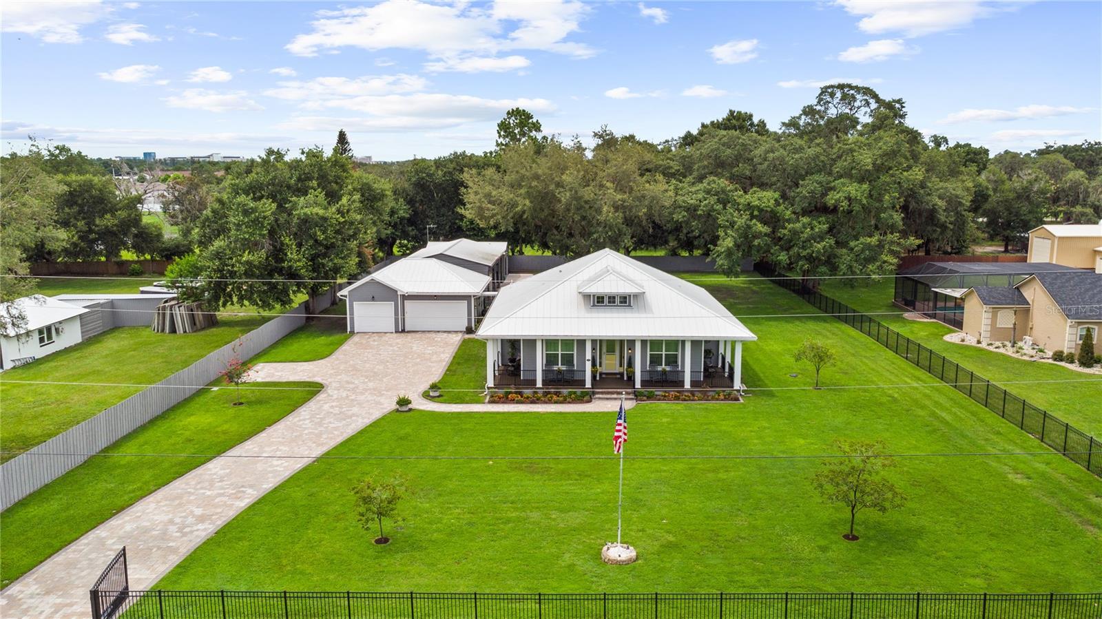 Luxury Custom Estate on 1 Acre with Detached 3-Car Garage & Two Metal Workshops. Welcome to this exceptional custom-built estate situated on a beautifully landscaped 1-acre homesite. Built in 2020 and meticulously maintained, this stunning 2,000 sq. ft. home offers 3 bedrooms, plus a dedicated office with custom built-ins, 2 luxurious bathrooms, an open-concept great room, dining area, laundry room, open wrap around front porch, and a screened rear porch designed for year-round Florida living. Located on a quiet dead-end paved road, you'll enjoy peaceful country living just minutes from major highways, Orlando International Airport, Lake Nona, and Saint Cloud. Inside, quality craftsmanship is evident throughout with 10-foot ceilings, 8-foot doors, porcelain tile flooring, custom wainscoting, Craftsman trim, 5½-inch baseboards, plantation blinds with programmable smart controls, and French doors with built-in blinds. Smart home features include Alexa-compatible lighting, Lutron controls, Nest thermostat, surround sound, security system, Ring doorbell, Wi-Fi connectivity, and custom lighting throughout. The gourmet kitchen features quartz countertops, an oversized island, dual built-in refrigerators (2025), gas range with pot filler, farmhouse sink, under-cabinet lighting, soft-close wood cabinetry, premium appliances, and two pantry areas. The office includes custom built-in desks and cabinetry with quartz work surfaces. A dedicated laundry/mudroom space with built-in cabinetry, quartz counters, front load washer and dryer on pedestals and sink makes chores a breeze. The spacious owner's suite offers a custom closet system and a spa-inspired bath with an oversized walk-in shower, dual rain and handheld shower heads, Kohler fixtures, and a private water closet. The guest bath features the same quality finishes. Enjoy Florida living from the Trex wraparound front porch or entertain on the screened rear porch complete with a summer kitchen featuring a KitchenAid gas grill, beverage refrigerator, sink with tankless water heater, surround sound, TV hookup, and ceiling fans. Built for efficiency and durability, the home includes concrete block construction with James Hardie siding, premium metal roof, spray foam insulation, double-pane windows, Rheem tankless gas water heater, whole-house water filtration system (2025), propane generator hookup, Lexan hurricane shutters, programmable irrigation, and extensive exterior lighting. The property also includes a detached 3-car garage connected by a covered walkway, plus two insulated metal workshops. The original 20' x 30' shop includes electricity, an automatic garage door, and a 10' x 30' lean-to. The newer 30' x 50' shop (2025) features drywall, custom paint, epoxy floors, electricity, and three Genie automatic garage doors. All garage and shop doors are MyQ smart enabled.
Additional exterior features include two sets of double gates with Ghost gate openers, full perimeter fencing, dedicated dog run, paver driveway and walkways, mature oak trees, beautiful landscaping, multiple water spigots, holiday lighting outlets, security cameras, and flood lighting. This one-of-a-kind property combines luxury, functionality, privacy, and exceptional craftsmanship in a highly desirable Central Florida location. Schedule your private showing today!