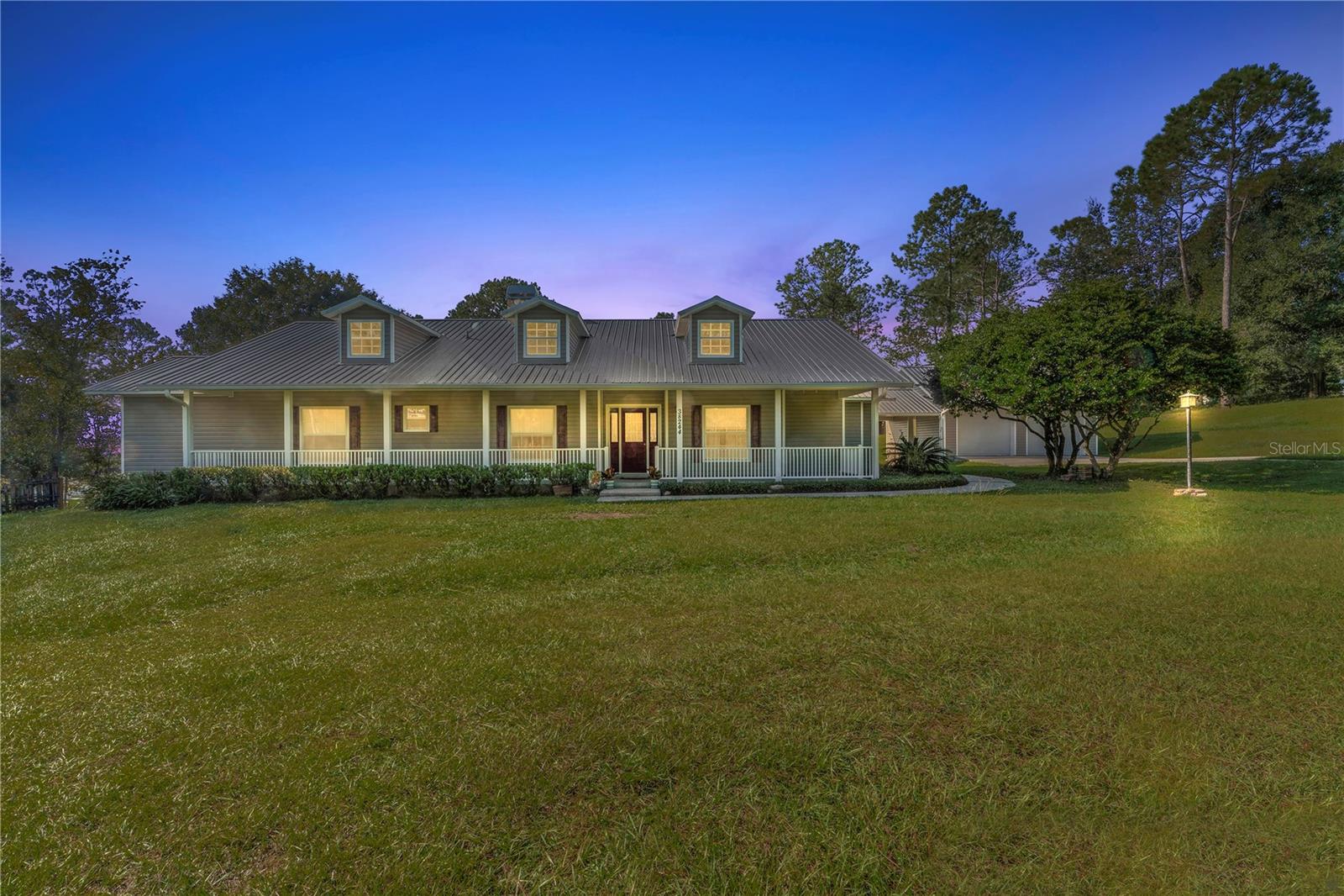 Looking for Peace & Tranquility? Let the Country roads bring you home to this 2002 Custom built 4 bedroom 2.5 bath home on 2.50 acres. Welcome to your picturesque oasis nestled in Dade City, FL. This stunning custom single-family home offers the perfect blend of modern living and natural beauty. The 2.5 acres are adorned with majestic trees, creating a tranquil, relaxing ambiance. As you enter the home from your 400sqft front porch you'll be greeted by a spacious and open living area that's perfect for entertaining, you will also notice the floor to ceiling stone gas fireplace with an amazing wood mantel. This added bonus is perfect for those crisp Florida nights .  The kitchen is a chef's dream come true, featuring a gas oven/cooktop, wood cabinets providing ample storage, plenty of counterspace, a huge walk in pantry AND center island with a double sink. There is also plenty of room to have an additional eat in area within the kitchen as there is a built in window seat with flip up storage.  The sellers have also left a built in custom murphy bed in one of the guest bedrooms for added convenience. All guest bedrooms are oversized and feature large closets for added storage. The master bedroom and ensuite are located on the back of the home and has as additional sitting area as well private entrance to the expansive fenced backyard . The ensuite features double sinks, and a large walk in shower, 2 large walk in closets complete this bedroom.  There is a large laundry room off the kitchen with a half bath, beyond the laundry is a 24x24 multi purpose room with double exterior sliding doors, this room was the original garage to this home but has can be converted to whatever your heart desires, this room also features an added panel for whole house generator hook up. The sellers recently added (2018) the covered breezeway and detached 24x24 garage. This garage has fully electric double roll up doors and a finished painted floor. The upgraded heavy gauge metal roofing was added in 2020 and complete the recent upgrades to this home.   The spacious backyard invites you to unwind and connect with nature. Gather around the firepit during crisp fall evenings. as this expansive yard provides ample space for recreational activities and any outdoor entertainment creating lasting memories with loved ones. There is a small barn on the property that housed chickens and will be the perfect setting for your mini farm. The property is fenced and crossed fenced. Come discover the joys of living in this remarkable county home where you can enjoy your peaceful private oasis yet be close to all amenities, don't miss your opportunity to make this custom home your forever home !