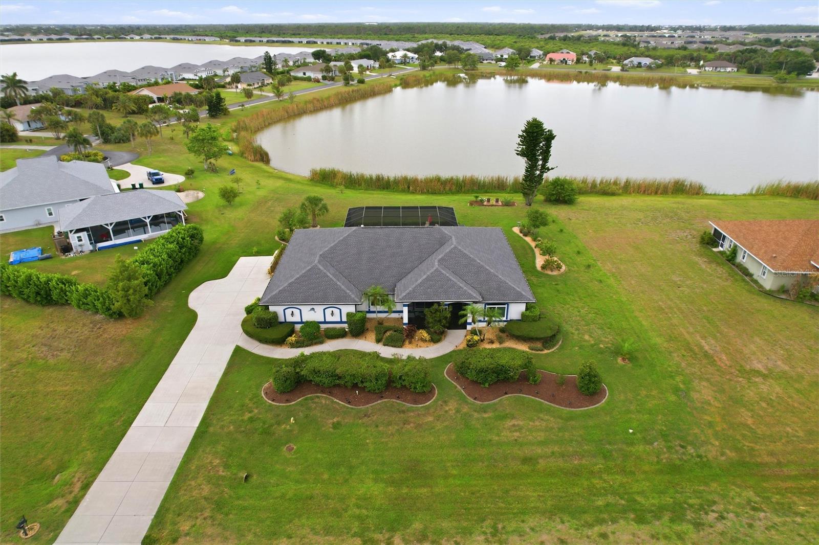 Welcome to your private lakeside retreat. This custom-built pool home offers 3 bedrooms +den, 2.5 bathrooms and 2,800 square feet of living space, perfectly positioned on a beautifully maintained one-acre homesite with breathtaking views of a tranquil lake. From the moment you arrive, you'll be impressed by the home's exceptional curb appeal, featuring lush tropical landscaping, an expansive driveway, and a screened front porch with attractive epoxy flooring. Recent improvements include a new roof (2020), new front windows (2024), two new hot water heaters (2026), and a pool heater replaced in 2025. Inside, the floor plan is designed for both comfortable living and effortless entertaining. Soaring ceilings, crown molding, abundant natural light, and luxury vinyl flooring create an inviting atmosphere throughout the main living areas. Large sliding glass doors seamlessly connect the great room to the outdoor living space while showcasing stunning lake and pool views. The dining room features decorative trim accents, and a large picture window that fills the space with natural light creating the perfect setting for everyday dining and special occasions. The beautifully updated kitchen combines style and functionality with crisp white cabinetry, solid-surface countertops, a center island, built-in appliances, recessed lighting, vaulted ceilings, and a striking blue and gray mosaic tile backsplash. Adjacent to the kitchen, the oversized walk-in pantry doubles as a functional utility space, complete with a washer and dryer, utility sink, additional refrigerator, extensive shelving, and abundant storage. Privately situated, the spacious owner's suite serves as a true retreat with direct access to the pool area, generous walk-in closets with built-in shelving, and a luxurious en-suite bath featuring an updated Roman shower, Jacuzzi tub, dual vanities, private water closet with a new toilet, and elegant finishes throughout. On the opposite side of the home, two guest bedrooms provide comfort and privacy. One bedroom offers direct access to the den/office, complete with a built-in desk, making it ideal for remote work, hobbies, or additional guest accommodations. The updated guest bathroom features an extended dual-sink vanity, walk-in tile shower, and freestanding soaking tub. Adding even more flexibility is the 24' x 11' AC/heated bonus room, perfect for a home office, fitness studio, media space, or guest overflow. Outdoor living takes center stage with an expansive covered lanai and screened pool area designed to take full advantage of the serene waterfront setting. The pool was resurfaced in 2021 and enhanced with a beautiful waterfall feature and new pavers. A ClearView pool cage, outdoor shower, and Sunseeker shade system were added in 2023, creating an exceptional outdoor oasis for year-round enjoyment. Ceiling fans and a convenient pool bath further enhance the space. Additional features include lake-fed irrigation, central vacuum system, Generac generator, hurricane shutters with remote-controlled protection for the lanai, updated ceiling fans, plumbing for a bidet in the primary bath, and a spacious 2-car garage with built-in shelving. Located within the intimate Casa De Meadows community, consisting of just 23 homes surrounding a scenic 10-acre lake, residents enjoy a peaceful setting where only non-motorized watercraft are permitted, preserving the natural beauty and tranquility of this exceptional waterfront neighborhood.