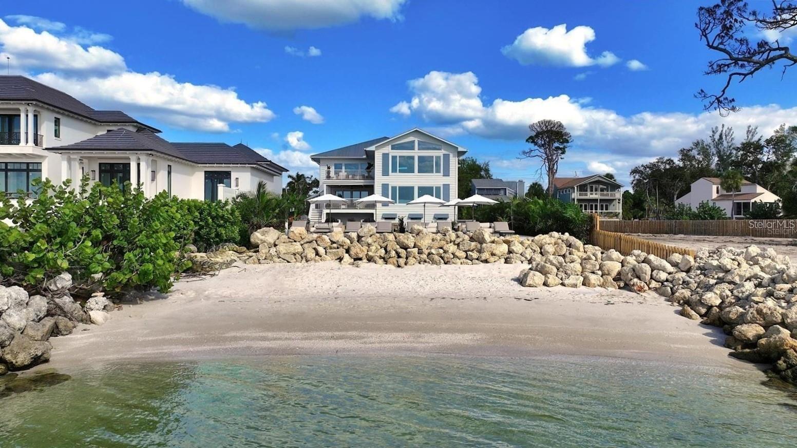 Under contract-accepting backup offers. Experience private beachfront coastal luxury at this one-of-one Siesta Key home, thoughtfully curated for comfort, style, and entertainment - by Pham Development. Perfectly positioned off the Gulf, with gorgeous ocean views throughout the rooms - you can watch a world-class sunset view from your master bedroom. Spanning over 6,468 square feet under air and 9,080 total square feet, this exquisite residence captures the essence of resort-style waterfront living on more than half an acre of pristine Gulf-front land. Be at ease with a surrounding elevated riprap shoreline and the imported rocks, offering both protection and privacy.

Pull into the property through the gated entry, with a paved driveway for ample parking. The ground level offers a 3-car garage, spacious private fitness studio with AC, large flex space/storage room, and huge game room that leads out to the truly special backyard - with premium turf, silica sand and a putting area. Host a sunset dinner with the full outdoor kitchen, including a freezer, wet bar, beverage center, ice machine, and 6-burner grill. Have a drink while sitting in the pool facing the ocean, relax in the champagne spa hot tub, or tan on the sun shelf. Put your toes in the sand area of the backyard, or take the paver steps down to the private beach and swim in the ocean - the ultimate paradise.

Wake up to the panoramic views of the Gulf of America and Sarasota Bay, that create a daily masterpiece of color and light, and have a coffee on the master bedroom's private balcony. With 6 bedrooms, 5 full bathrooms, and 2 half baths, you can host more family and guests - along with the second living room/media room. All of the bedrooms have custom built-in closets, and the spacious ocean-view master bathroom leads to two spacious walk-in closets. The home features high-ceilings, beautiful hardwood flooring throughout, and cypress beams. The living and dining room area have a fireplace, and the open-floor plan leads out to another large balcony overlooking the ocean. Enjoy the gourmet custom kitchen with Thermador gas appliances, a walk-in pantry, and an extra large quartz island with seating.

An elevator connects the 3-level home through the grand living spaces that flow seamlessly toward the water, blending indoor sophistication with the beauty of the coast. The lush tropical landscaping evokes the serenity of a private resort. Located just minutes from Siesta Beach, the Village, and the North Siesta Bridge, this rare coastal jewel offers the ultimate combination of elegance, exclusivity, and Gulf-front tranquility—a move-in ready residence truly without equal on Siesta Key.