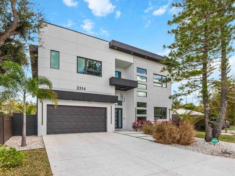 A statement of modern elegance in the heart of Sarasota, this exceptional Arlington Park residence delivers refined luxury, architectural presence, and elevated design at every turn. Offering 5 bedrooms, 5.5 bathrooms, and 3,651 square feet under air, this custom-built home was thoughtfully designed for those who appreciate both sophisticated entertaining and comfortable everyday living. From the moment you enter, soaring 12-foot ceilings and a dramatic staircase create an unforgettable first impression. The main living spaces are open, expansive, and filled with natural light. A designer kitchen anchors the home, showcasing solid wood cabinetry, quartz countertops, an oversized waterfall island, and premium Thermador appliances which are perfectly suited for culinary enthusiasts and elegant gatherings alike. A custom built-in feature wall enhances the living area with both style and function. Sliders seamlessly connect indoor and outdoor spaces, creating effortless Florida living. A private first-floor office offers a quiet retreat for work or study. Upstairs, 10-foot ceilings and rich hardwood flooring continue the home’s elevated aesthetic. The owner’s suite is a true sanctuary, complete with a private balcony overlooking the backyard, custom vanity, a soaking tub, and an oversized walk-in shower finished with striking designer tile. Each additional bedroom features its own en-suite bath and walk-in closet, ensuring comfort and privacy for family and guests. A spacious second-floor den provides flexible space for a media room, lounge, or game area. The outdoor setting rivals a private resort. The saltwater pool with waterfall and sun shelf is complemented by a spa, outdoor shower, and dedicated pool bath. A modern aluminum pergola adds architectural interest and shaded relaxation, while the lanai invites seamless entertaining year-round. No detail was overlooked: impact-rated windows and doors, epoxy-finished 2.5-car garage, irrigation system, integrated indoor/outdoor speakers, pre-wiring for security cameras, and dual A/C systems for optimal efficiency. Located in highly desirable Arlington Park, this home places you minutes from downtown Sarasota, Sarasota Memorial Hospital, and the area’s renowned dining and cultural destinations. World-class beaches including Siesta Key and Lido Key are just a short distance away. This is more than a home...it is a lifestyle defined by quality, design, and distinction. All information provided by the sellers is deemed reliable but is not guaranteed. Buyers are encouraged to verify all information independently.