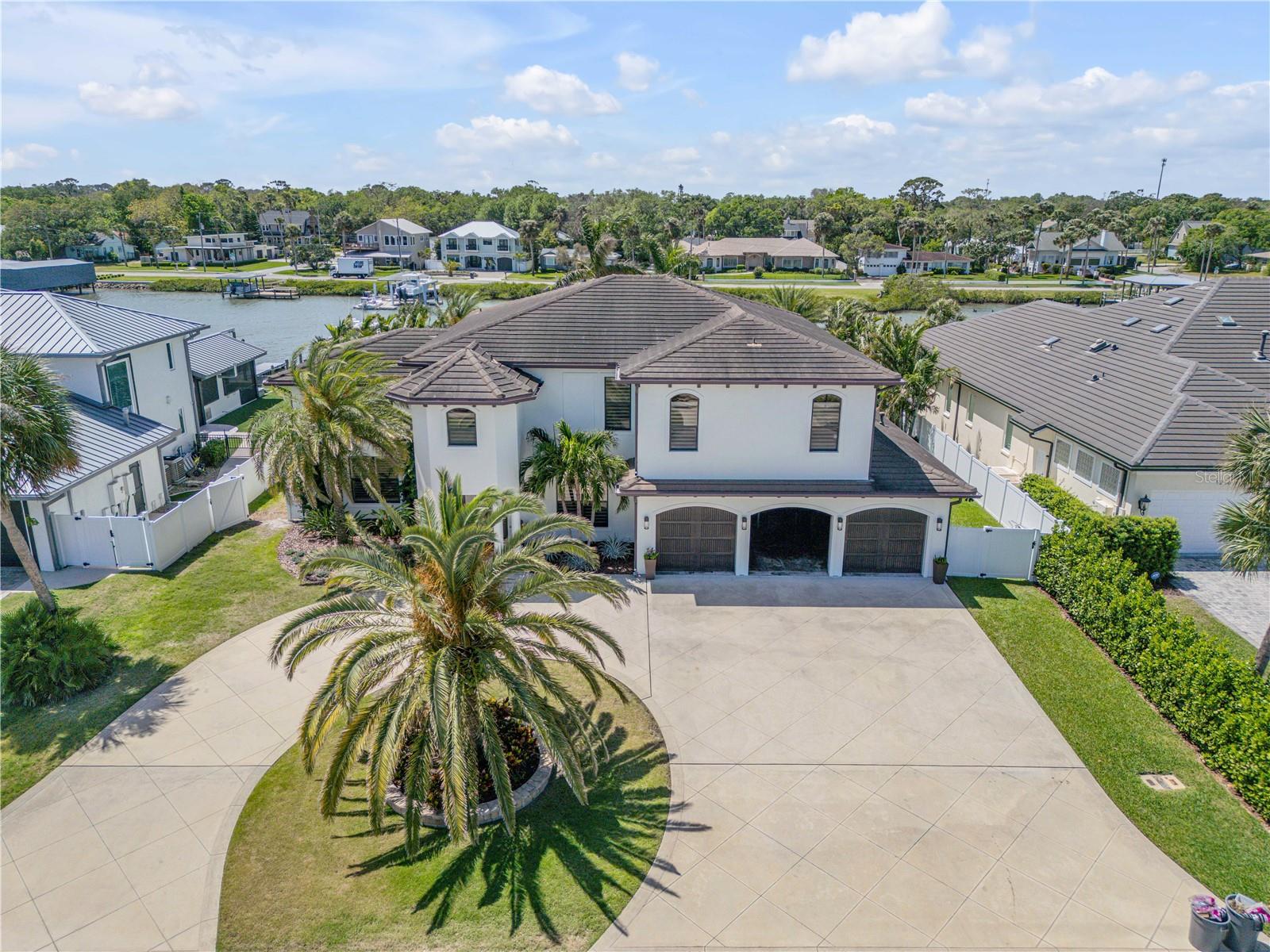Welcome to 1212 Commodore Dr — a rare opportunity to own in the exclusive, gated community of Yacht Club Island Estates in beautiful New Smyrna Beach! Nestled on a quiet gated waterfront neighborhood, this 4-bedroom, 5-bath home offers the perfect blend of privacy, comfort, and coastal living.

Step inside to an inviting, open floor plan with soaring ceilings, abundant natural light, and spacious living and dining areas — ideal for relaxing or entertaining. The kitchen offers plenty of storage, a breakfast nook, and views of the lush backyard. The split bedroom layout provides added privacy, while the primary suite features a walk-in closet and en-suite bath.

Step outside to your very own backyard retreat! The resort style pool is surrounded by tropical landscaping, creating the ultimate setting for relaxation or entertaining. The outdoor kitchen is fully equipped with a built-in grill, sink, refrigerator, and bar seating — perfect for weekend gatherings, sunset dinners, or quiet evenings under the stars.

Located in Yacht Club Island Estates — a private, gated enclave on the Intracoastal Waterway, and just minutes from marinas, beaches, and charming Canal Street dining & shopping. Golf cart friendly and perfect for boating enthusiasts, this sought-after neighborhood offers both security and a serene coastal lifestyle.
Don't miss your chance to live in one of best-kept secrets in New Smyrna Beach’s ONLY waterfront gated community!

This is Florida living at its finest — your dream home awaits!