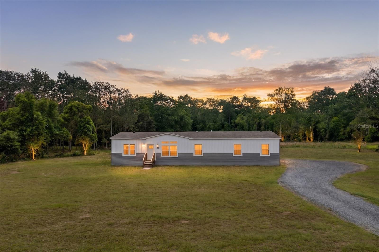 Virtually Staged. Welcome to your private North Florida retreat! This is your chance to own a slice of heaven nestled on 50 beautiful acres near Lake Santa Fe. This 2023 4-bedroom, 3-bathroom upgraded manufactured home offers the perfect blend of modern comfort, peaceful country living, and plenty of room to roam. With 2,254 square feet of living space, the thoughtfully designed split floor plan features both a living room and a separate family room, providing flexibility for entertaining, working from home, or everyday living. The open concept kitchen is the heart of the home, showcasing a large center island, custom backsplash, abundant cabinetry, and seamless open flow into the dining and family areas. Built with quality and durability in mind, the home features 9-foot ceilings throughout, full-house OSB wrap construction, a 50-gallon water heater, generous storage, and a spacious utility/laundry room. The primary suite offers a private retreat with a large walk-in closet, dual vanities, a soaking tub, and a separate shower. Three additional bedrooms and two additional full bathrooms provide plenty of space for family and guests. Step outside and enjoy the freedom that 50 acres provide. Whether you’re dreaming of bringing horses or livestock, creating riding trails, gardening, hunting, outdoor recreation, or simply enjoying the privacy and natural beauty of North Florida, this property offers endless possibilities. Conveniently located less than 5 minutes from Santa Fe Lake Park with public boat access, playgrounds, and picnic areas, and approximately 25 minutes from Gainesville, you’ll enjoy the perfect balance of seclusion and accessibility. If you’ve been searching for a newer home with acreage, privacy, and unlimited potential, this exceptional property is one you won’t want to miss. The home is located in flood zone X.  Schedule a private showing today! Buyer should verify all information.