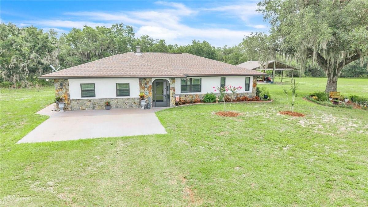 Natural beauty, ultimate privacy, and country charm define this exceptional 3-bedroom, 2-bath pool home, perfectly situated on more than 5 acres in the peaceful rural community of Arcadia. Surrounded by majestic oak trees draped in Spanish moss, beautifully landscaped grounds, a private pond, and expansive green space, this property offers the ideal setting for those seeking a tranquil lifestyle with room to roam. Bring your horses, livestock, equipment, and recreational toys—this AG-5 zoned property is designed for country living. The acreage allows for agricultural use, livestock, gardens, outbuildings, and recreational vehicles, providing endless possibilities to create the rural lifestyle you've always envisioned. A 26x36 pole barn and an additional storage building with a garage door offer abundant space for equipment, hobbies, and storage. Inside, the home offers over 1,600 square feet of comfortable living space with a bright, open floor plan designed for everyday living and entertaining. The spacious living and dining areas are complemented by a versatile bonus room that can easily serve as a fourth bedroom, home office, den, or flex space. Stylish accent walls, wood-look tile flooring throughout the main living areas, and a stunning stone wood-burning fireplace create warmth and character throughout the home. The beautifully updated kitchen blends style and functionality, featuring stainless steel appliances, white wood cabinetry with modern hardware, granite countertops, a subway tile backsplash, and a farmhouse sink positioned beneath a window overlooking the property. A tray ceiling with statement lighting adds architectural appeal, while the open layout flows seamlessly into the dining area. Sliding glass doors lead directly to the pool lanai, creating the perfect indoor-outdoor living experience. Outdoor living takes center stage with an expansive screened lanai and sparkling pool overlooking the fenced acreage and picturesque surroundings. Whether enjoying your morning coffee, hosting family gatherings, or relaxing poolside at sunset, you'll appreciate the peaceful views and unmatched privacy. The primary suite serves as a private retreat with direct lanai access through sliding glass doors, a walk-in closet, and an updated en-suite bathroom featuring a freestanding dual-sink vanity, decorative tile backsplash, and a shower/tub combination. Two additional guest bedrooms, one currently utilized as a home office, feature built-in closets and share an updated guest bathroom with a dual-sink vanity and walk-in tiled shower. Both bathrooms are finished with durable slate tile flooring, adding rustic elegance and timeless appeal. A convenient laundry area is located in the hall closet for efficient use of space. This well-maintained home also offers valuable updates and features, including a new roof (2023), A/C system (2022), impact-resistant windows, hot water heater (2021), and a water softener system. Conveniently located near local waterways, Gulf beaches, dining, shopping, golf courses, and public parks, outdoor enthusiasts will enjoy easy access to walking and biking trails, picnic areas, and boat ramps leading to the Peace River, Myakka River, Charlotte Harbor, and the Gulf of Mexico. Despite its peaceful, secluded setting, the property offers quick access to Interstate 75 for easy commuting and travel. Experience the perfect blend of privacy, functionality, and Florida country living on this remarkable Arcadia estate.