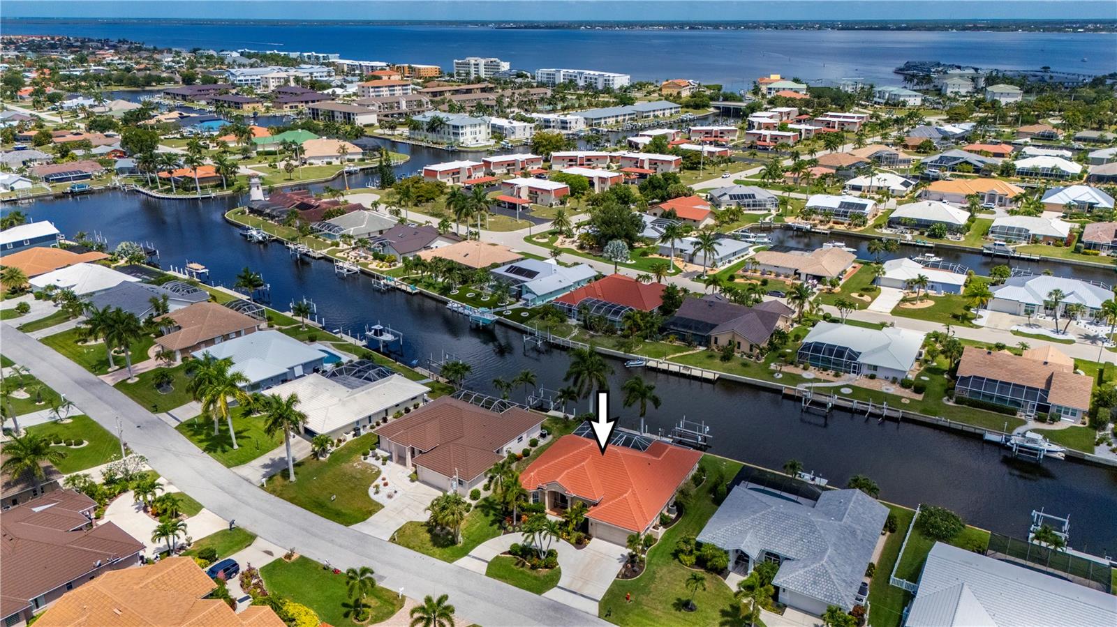 As the sun begins to set over the canal, this exceptional FERO built waterfront residence transforms into a private coastal retreat designed for elegant living and unforgettable entertaining. Nestled within the powerboat section of Punta Gorda Isles, the home captures the beauty of Southwest Florida living with breathtaking water views, seamless indoor outdoor flow, and luxurious designer finishes throughout. Soaring stepped ceilings, crown molding, tile flooring, and expansive zero edge pocket sliders create an atmosphere that feels both grand and inviting, while natural light pours into every thoughtfully designed space. At the center of the home, the gourmet kitchen serves as both a showpiece and gathering place, anchored by a dramatic 5x9 single slab quartz island and surrounded by upgraded custom cabinetry and a suite of top tier appliances including an Italian oven, smart refrigerator, drawer microwave, wine cooler, and farmhouse sinks in both the kitchen and laundry room. A panoramic bay window frames tranquil canal views, bringing the outdoors into everyday living and dining spaces designed for effortless entertaining and relaxed waterfront living. Privately tucked away, the primary suite offers a serene escape with direct access to the lanai, expansive walk in closet with custom built ins, and a spa inspired ensuite featuring dual vanities, a jacuzzi soaking tub, and an oversized walk in shower with pocket sliders to the laundry room from the closet. Two guest bedrooms provide inviting accommodations for family and visitors, each thoughtfully designed to reflect the home’s refined yet comfortable atmosphere. Outside, the expansive lanai becomes the true heart of the home as glowing sunset skies reflect across the water and create an unforgettable backdrop for evenings spent poolside. The outdoor living area features a sparkling pool, an outdoor kitchen with upgraded grill and refrigerator, and panoramic unobstructed canal views that elevate every moment. Boating enthusiasts will appreciate the 30 foot concrete dock and 10,000 pound boat lift with new motors and cables, offering quick access to Charlotte Harbor and an easy ten minute cruise to Fisherman’s Village. Complete with updated lighting, a 2023 roof, and pristine move in ready condition, this extraordinary residence embodies sophisticated waterfront living at its finest.
