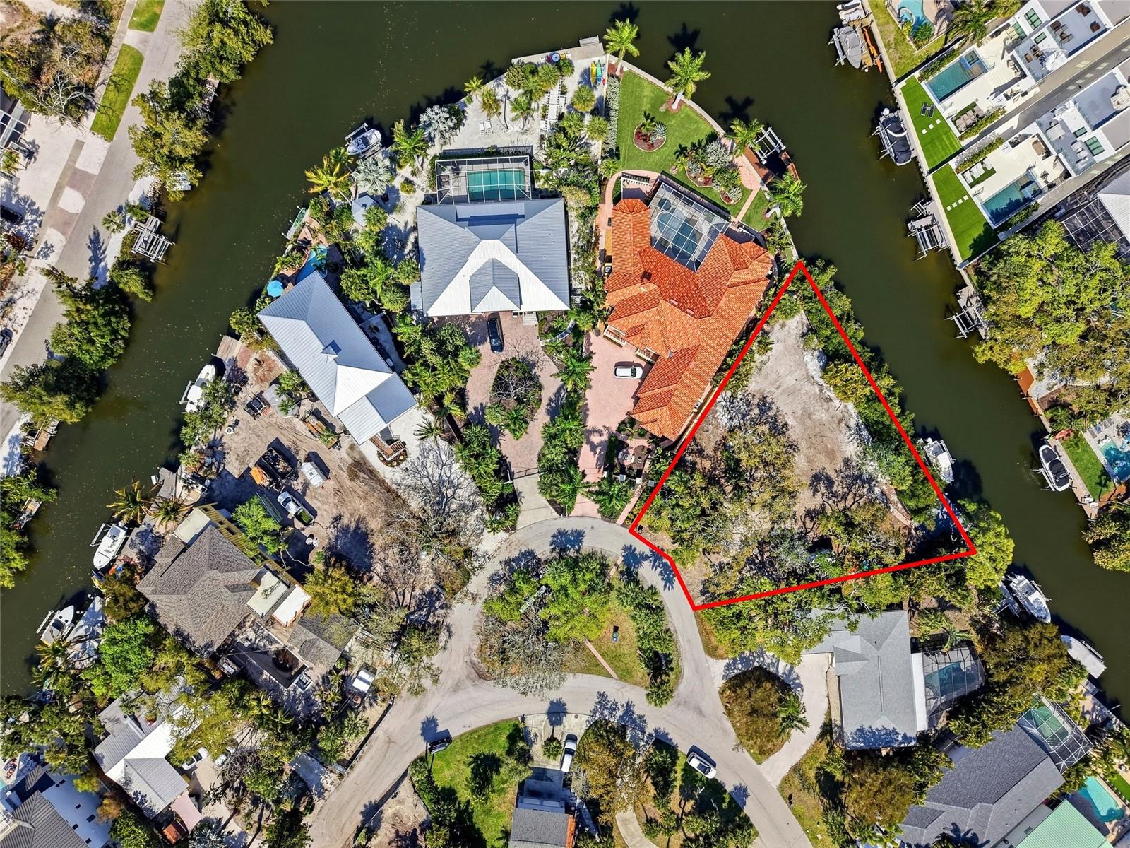 A rare opportunity to secure a true waterfront estate-sized homesite in the highly sought-after Palm Island enclave of Siesta Key. Located at the end of a quiet loop on Island Circle, this oversized 15,500 square foot pie-shaped double lot offers an exceptional 180+ feet of water frontage, creating a private, expansive setting rarely found this close to the beach. Surrounded by lush natural mangroves and multimillion-dollar residences, this property delivers the perfect balance of privacy, exclusivity, and direct boating access. A standout feature of the property is the grandfathered in 20x24 dock, significantly larger than what current regulations allow.  Paired with a 14,000-pound boat lift and existing water and electric connections, for boating enthusiasts, this is not just a convenience, it’s a major asset that cannot be replicated today. This homesite offers a strong foundation for new construction and the opportunity to design and build a custom waterfront estate tailored to your vision. The lot’s unique shape and size allow for a larger footprint, creative architectural design, and maximization of water views. Palm Island is one of Siesta Key’s best kept secrets, an intimate community of fewer than 140 homes known for its quiet streets, limited traffic, and strong sense of privacy and community. The property is ideally positioned across from a small community green space and just minutes from the world-renowned Siesta Key Beach, consistently ranked among the top beaches in the United States.
Whether you are looking to build a full-time residence, a seasonal retreat, or a long-term investment property, this lot presents a rare combination of size, location, waterfront access, and redevelopment potential that is becoming increasingly difficult to find on Siesta Key.
Opportunities like this are limited, especially with irreplaceable features like this dock and water frontage.