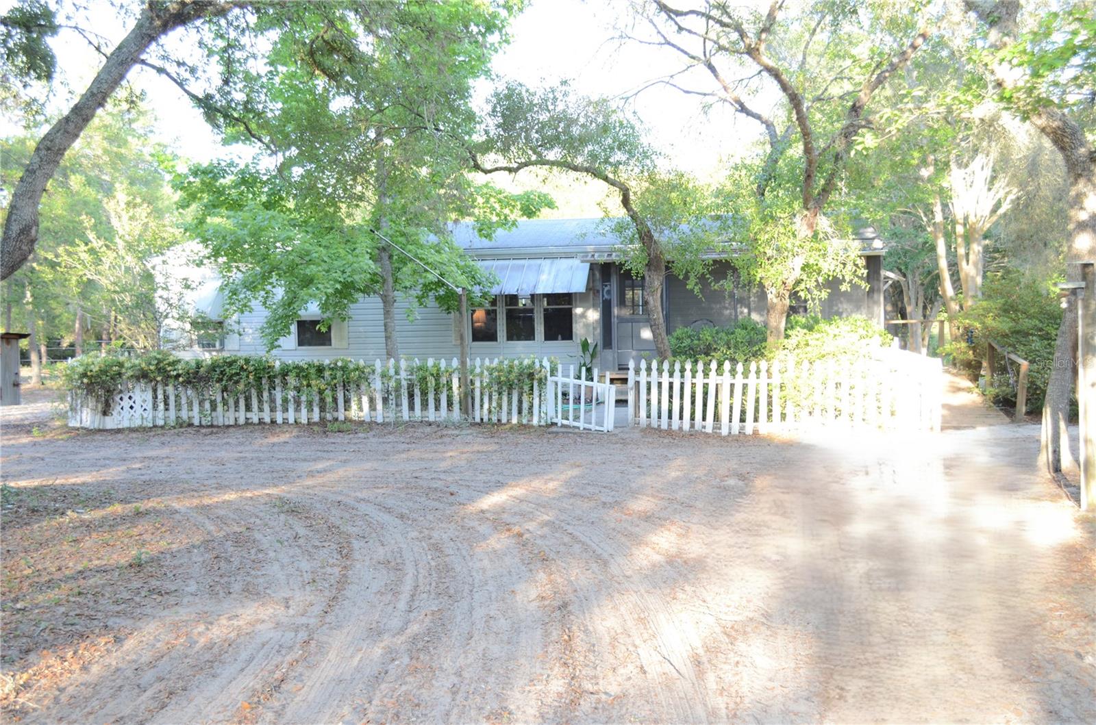 Set along the scenic Ocklawaha River, this 26.3 acre property offers a rare opportunity to create your own private nature retreat. Ideal for outdoor enthusiasts, the land provides a peaceful setting to enjoy wildlife, explore nature, and take advantage of a wide range of outdoor activities.
Approximately 19 acres are wooded, offering natural privacy and a true sanctuary like setting, while the remaining open areas are well suited for horses, gardening, or recreational use. The property includes a pole barn and multiple storage structures, making it a great option for equestrian or agricultural use.
The property extends toward the Ocklawaha River, with wooded areas leading to the water and potential for kayaking, boating, and fishing.
Two homes are located on site, providing flexibility for multigenerational living, rental income, or guest accommodations. The property also includes an electric hookup for an RV or camper.
Conveniently located between Ocala National Forest and The Villages, you will have easy access to natural springs, outdoor recreation, shopping, dining, and medical facilities. Nearby Lake Weir offers additional opportunities for boating, fishing, and waterfront dining, including Eaton’s Beach and Gator Joe’s. Enjoy the five town squares in The Villages offering live bands and DJs while still experiencing the peace and quiet of country living.
This property offers the perfect balance of seclusion and convenience, close to growing, populated areas, yet tucked away enough to enjoy a quiet, private lifestyle.