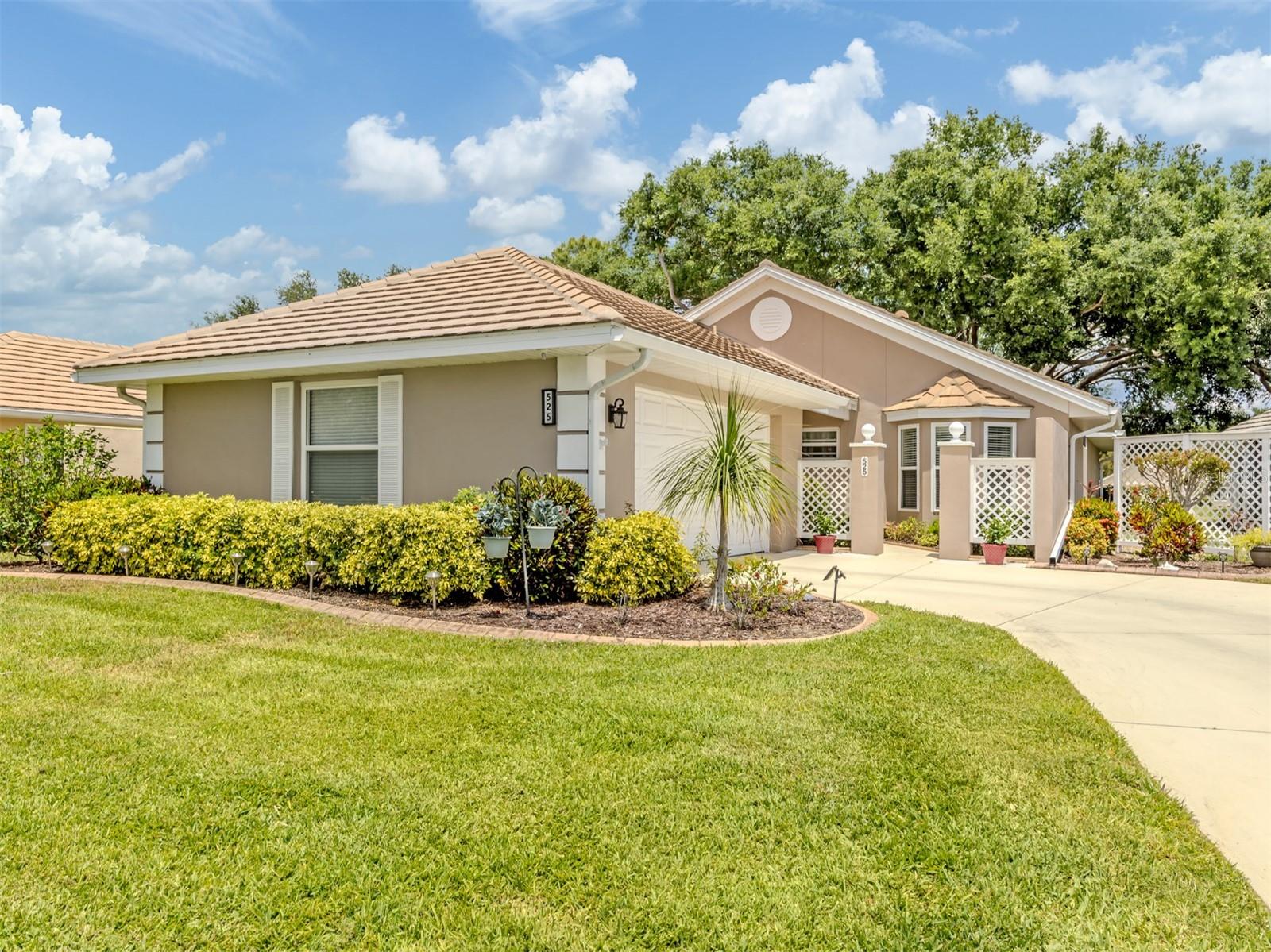 What a location! Golfers, tennis and pickleball players, swimmers and all seeking to relax, this attractive home, surrounded by mature landscaping, a large front lawn and a sweeping view across a large pond, provides the best of Plantation. With hurricane-impact windows and shutters throughout, a recent 2017 tiled roof and an updated storm-resistant garage door, the residence offers security. The garage has a number of wall cabinets, epoxy flooring and contains a new hot water heater. With a ceramic tiled floor, the kitchen has granite counters, a new Bosch dishwasher, a new KitchenAid® island cooktop and modern appliances. Solid wood cabinets and a breakfast nook provide a comfortable ambience. With high ceilings and open spaciousness, the dining and living areas have ceramic-tiled flooring that enhances the entertaining appeal of the area. The adjoining, substantial family room, with floor-to-ceiling windows, overlooks a large pond with a fountain that is surrounded by plantings and trees, offering often abundant views of wildlife. Such views are also available from the ceramic-tiled Florida room, providing open-air enjoyment. The high-ceiling primary bedroom provides a bay window that also overlooks the pond. The well-lit primary bath has a glass-enclosed shower, a large built-in closet, a granite sink and a substantial walk-in closet. The guest bedroom has a bay window and en-suite bath with shower and tub along with a granite-countered sink. The third bedroom, or den, has a spacious closet and an atrium that holds plants, which enhance the look of the room. This residence is located in the maintenance-free community of Clubside Villas at the Plantation, with its clubhouse and heated saltwater pool. It is immediately adjacent to Plantation Golf and Country Club with its two golf courses and tennis and pickleball courts. Optional memberships are available. Nearby is Wellen Park with new shops, restaurants and the spring training ballpark of the Atlanta Braves at Cool Today Park. Also nearby is the city of Venice's shopping, restaurants, beaches and water sports.